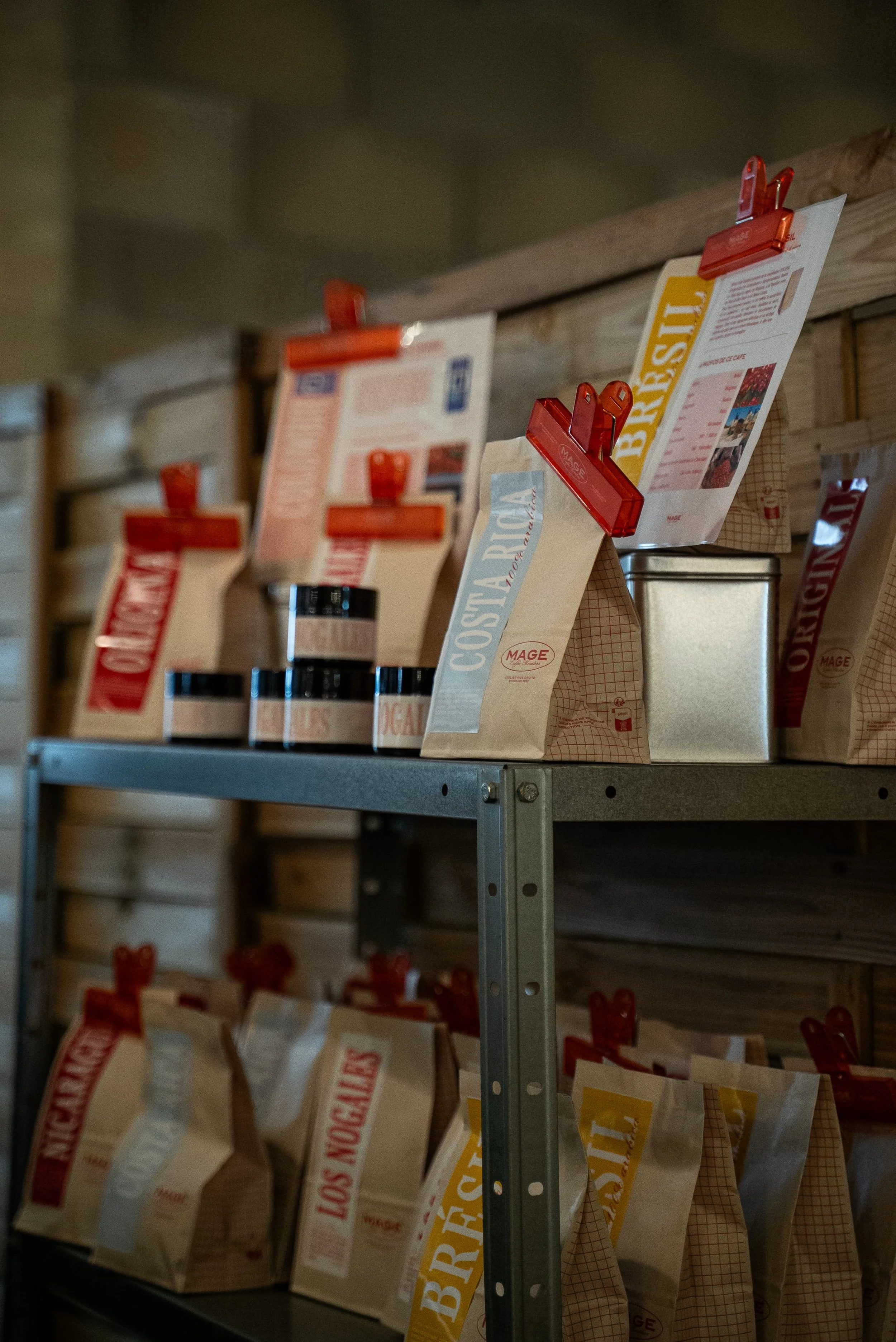 Différentes sortes de sacs de farine en vrac, suspendus avec des pinces en plastique rouges sur une étagère en métal.