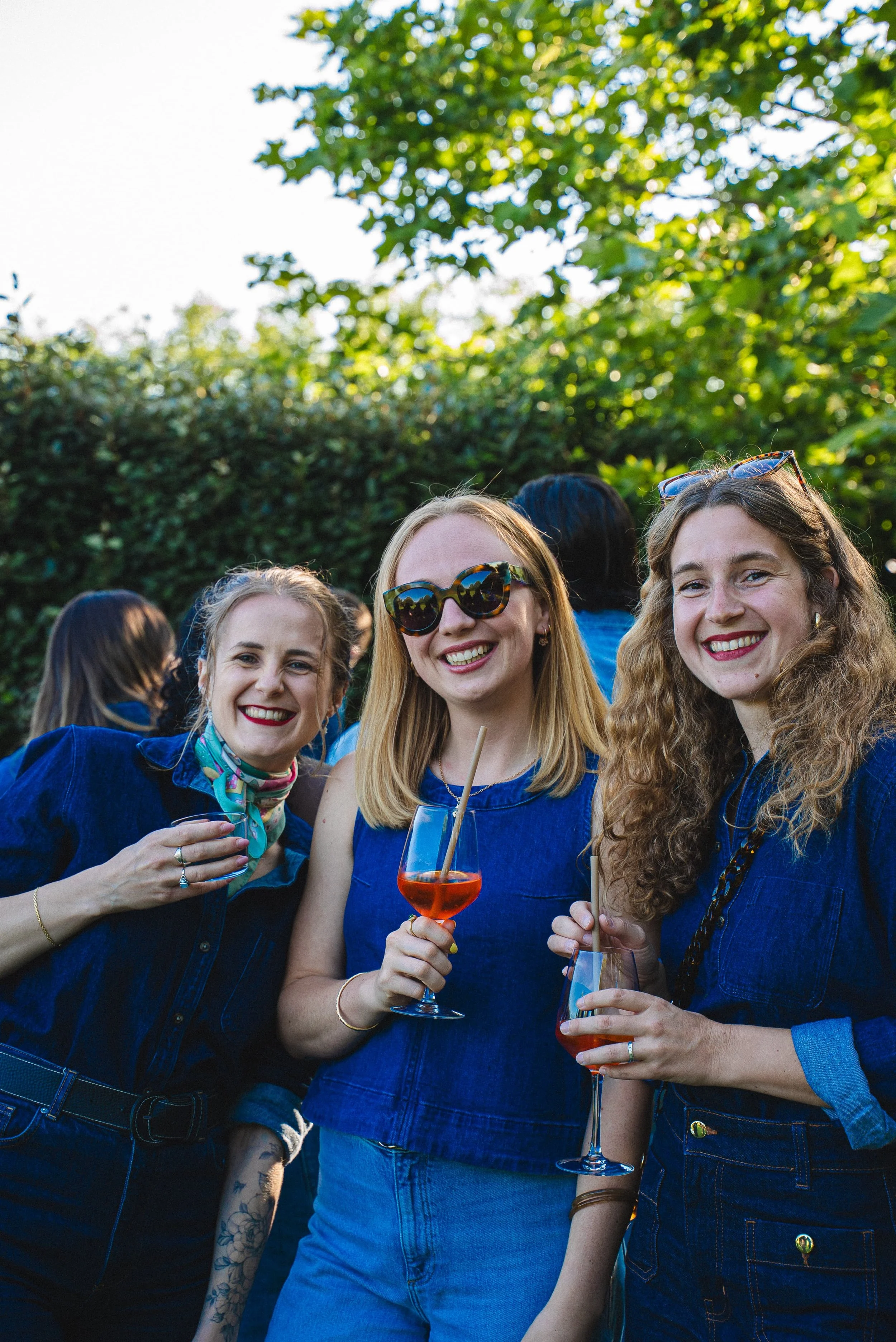 Groupe de femmes souriantes lors d'une fête en plein air, tenant des verres de cocktail.