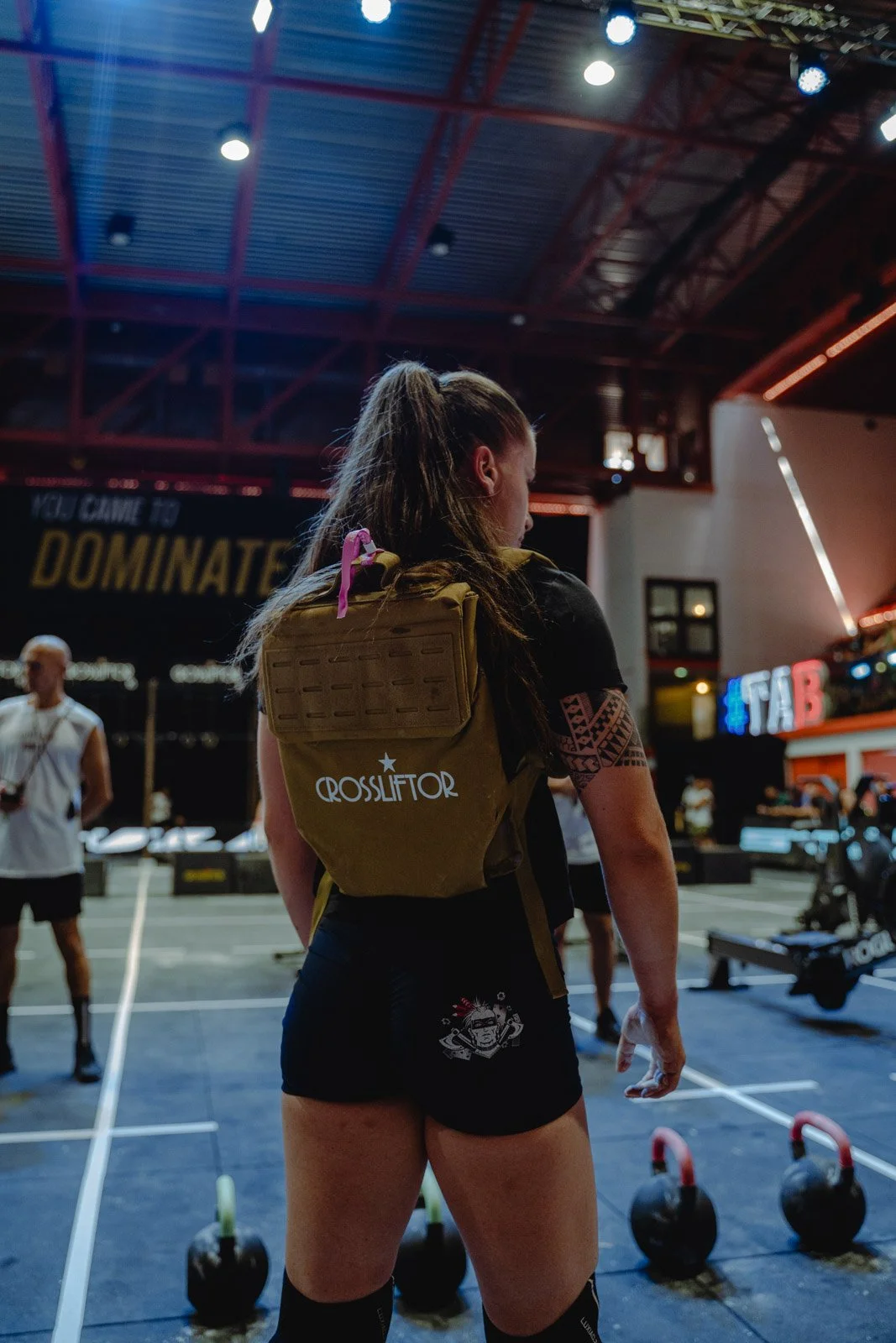 Femme portant sac à dos CrossLifter dans une salle CrossFit entourée d'haltères à Bordeaux — photographe CrossFit Voar by Tim