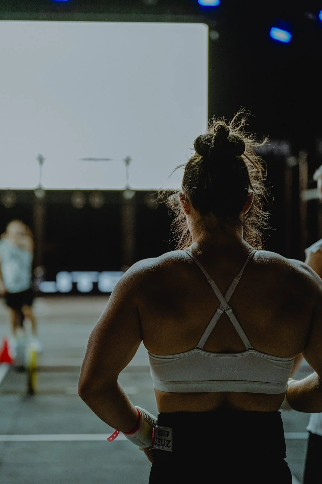 Femme de dos en débardeur blanc regardant un écran lors d'une compétition CrossFit en Nouvelle-Aquitaine — photographe CrossFit Voar by Tim