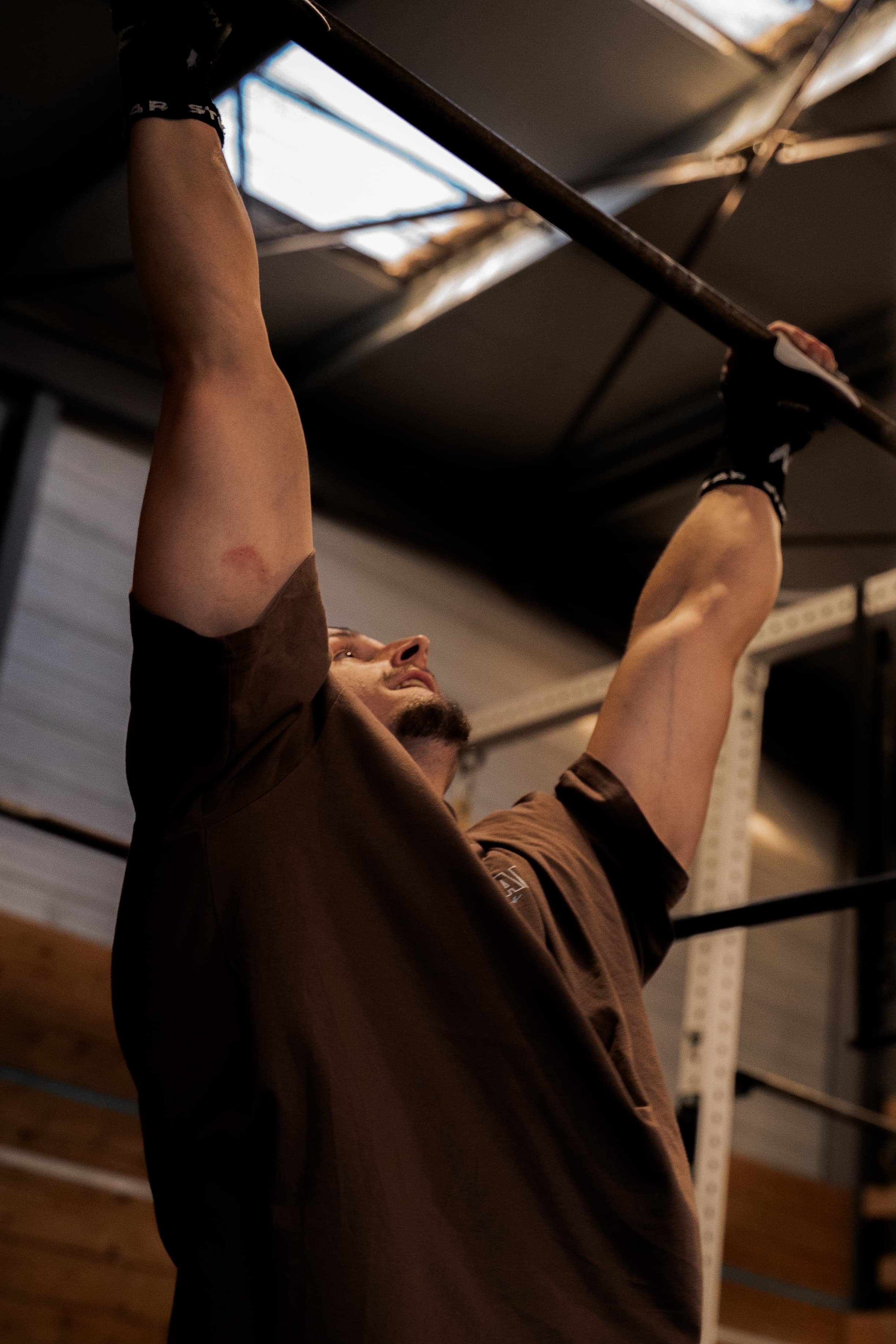Un homme effectuant un exercice de musculation en soulevant une barre verticale dans une salle de sport.