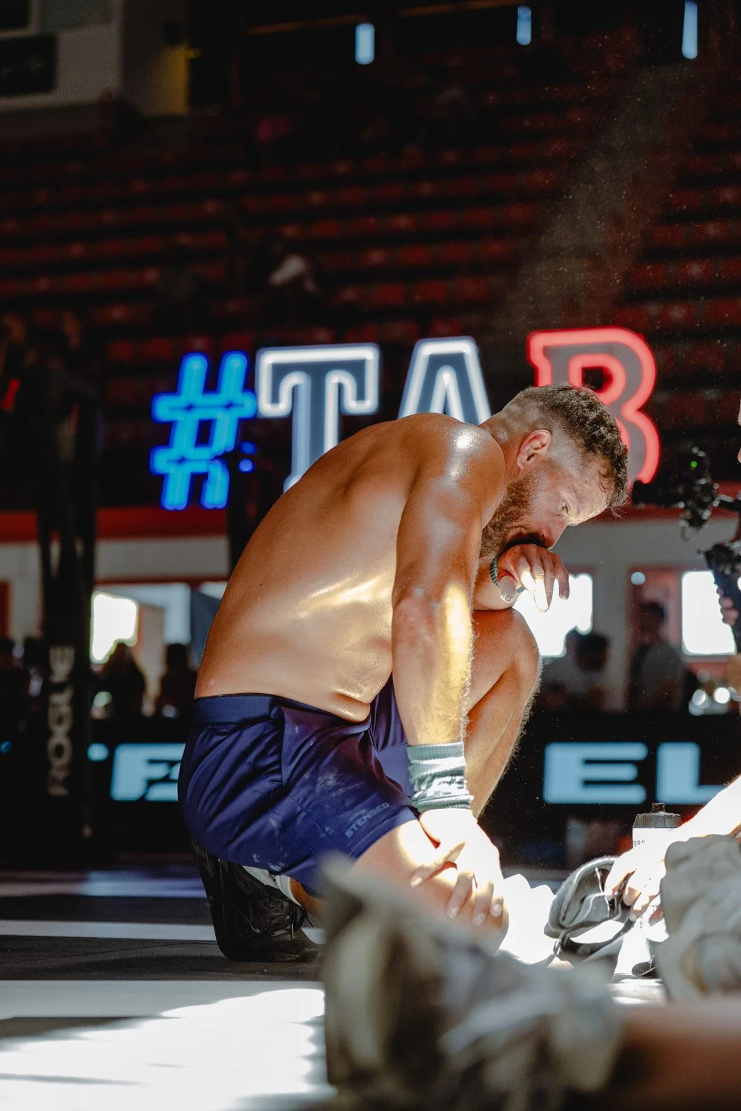 Homme musclé en débardeur s'essuyant la sueur dans une salle CrossFit avec panneau lumineux — photographe CrossFit Voar by Tim