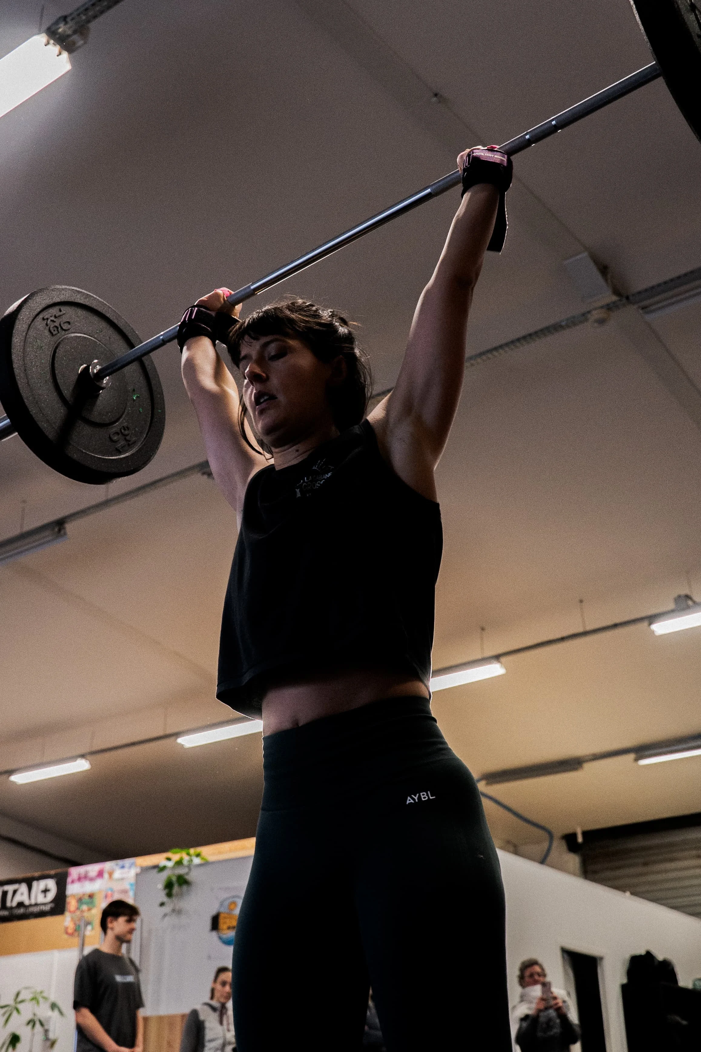 Une femme soulève une barre avec des poids dans une salle de sport