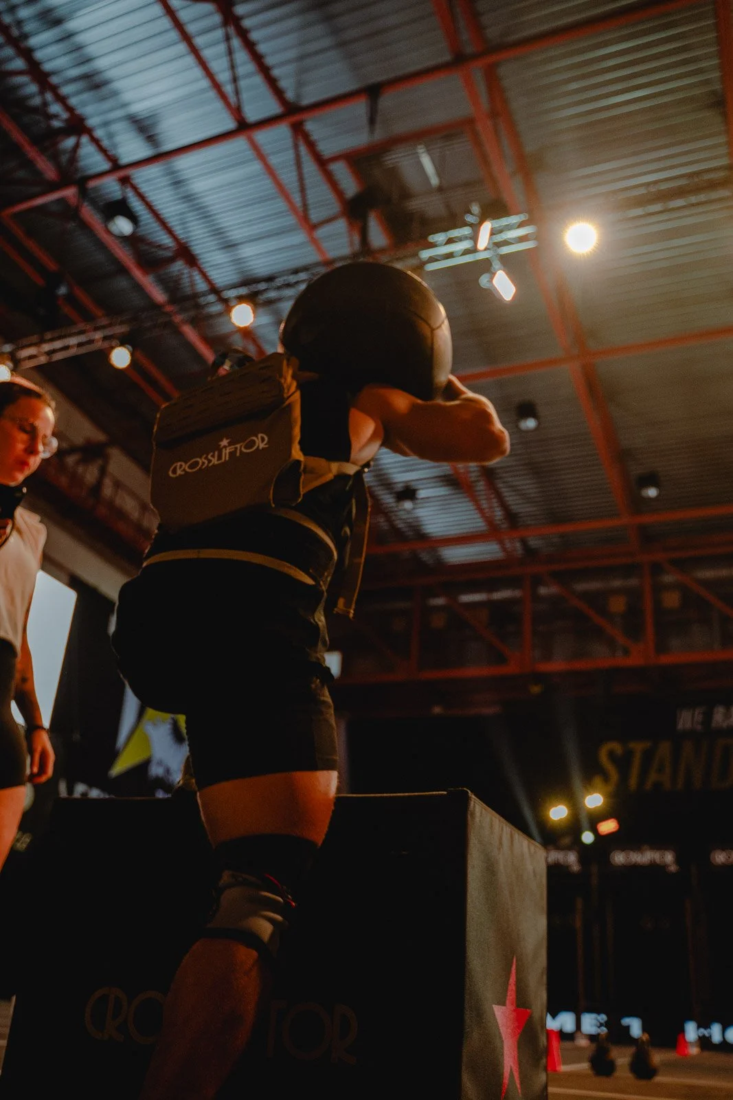 Femme avec sac à dos lors d'une séance CrossFit sous projecteurs dans une salle à Bordeaux — photographe CrossFit Voar by Tim