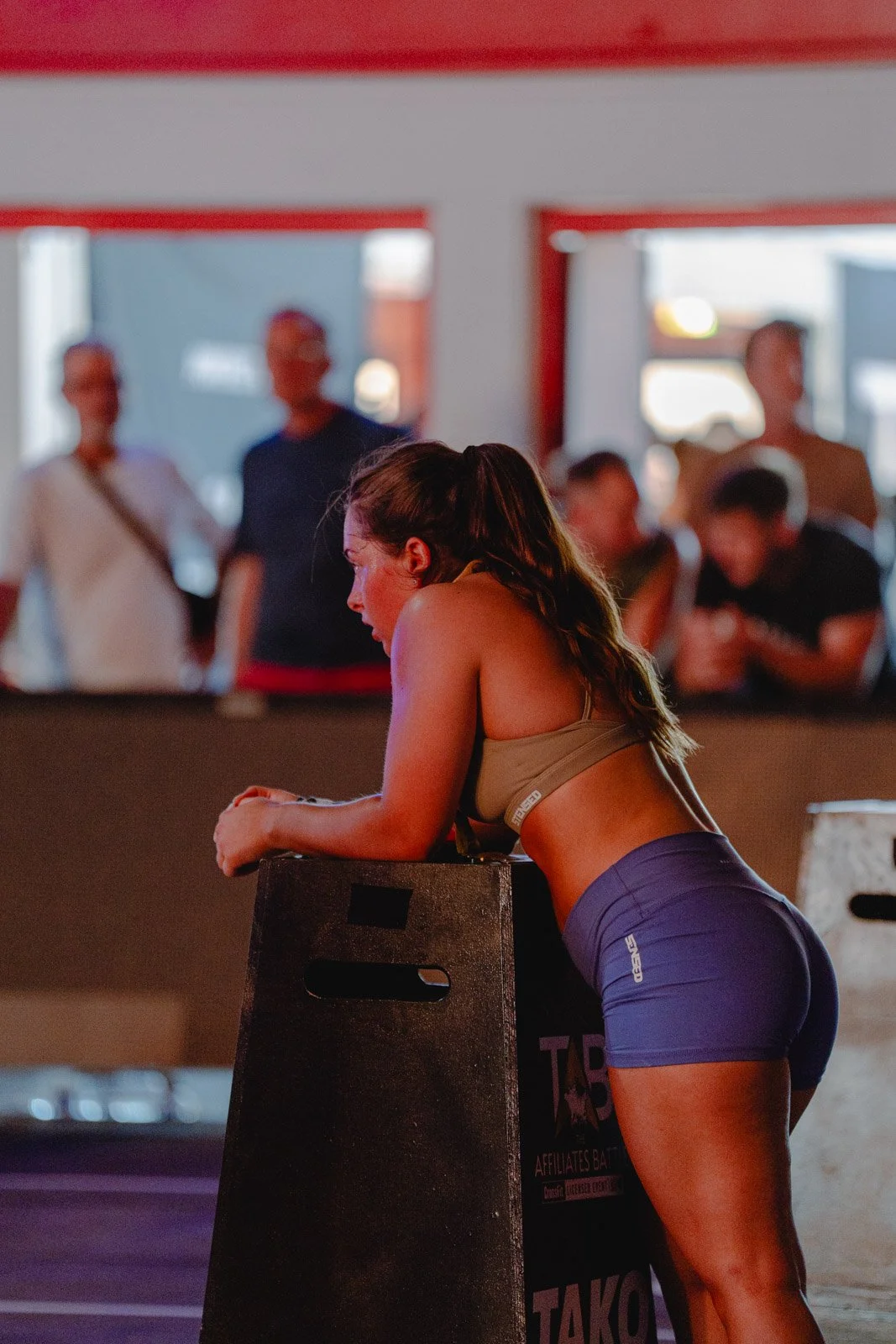 Femme en vêtements de sport s'appuyant sur une caisse CrossFit dans une salle de sport — photographe CrossFit Voar by Tim
