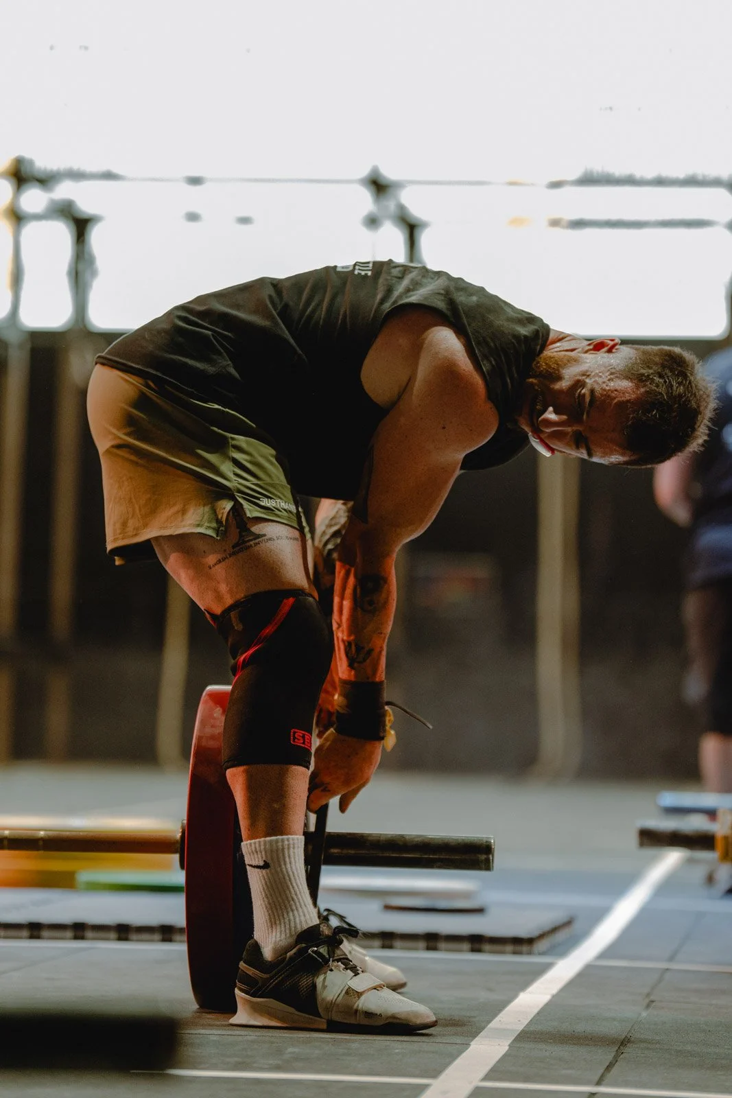 Homme en entraînement de musculation avec bandage genou, soulevé de barre lors d'une compétition CrossFit à Bordeaux — photographe CrossFit Voar by Tim