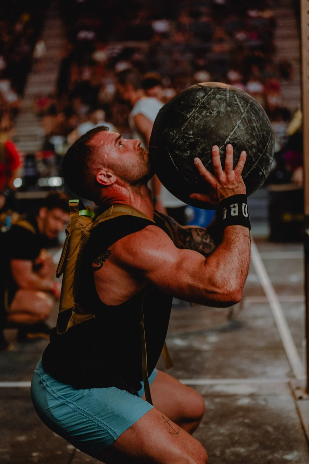 Homme musclé soulevant une medecine ball avec sac à dos CrossLifter lors d'une compétition CrossFit à Bordeaux — photographe CrossFit Voar by Tim