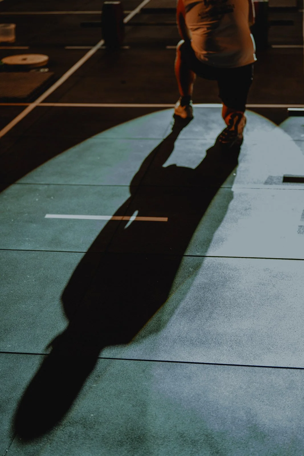 Personne en tenue de sport sur tapis d'entraînement sous lumière tamisée, salle CrossFit Bordeaux — photographe CrossFit Voar by Tim