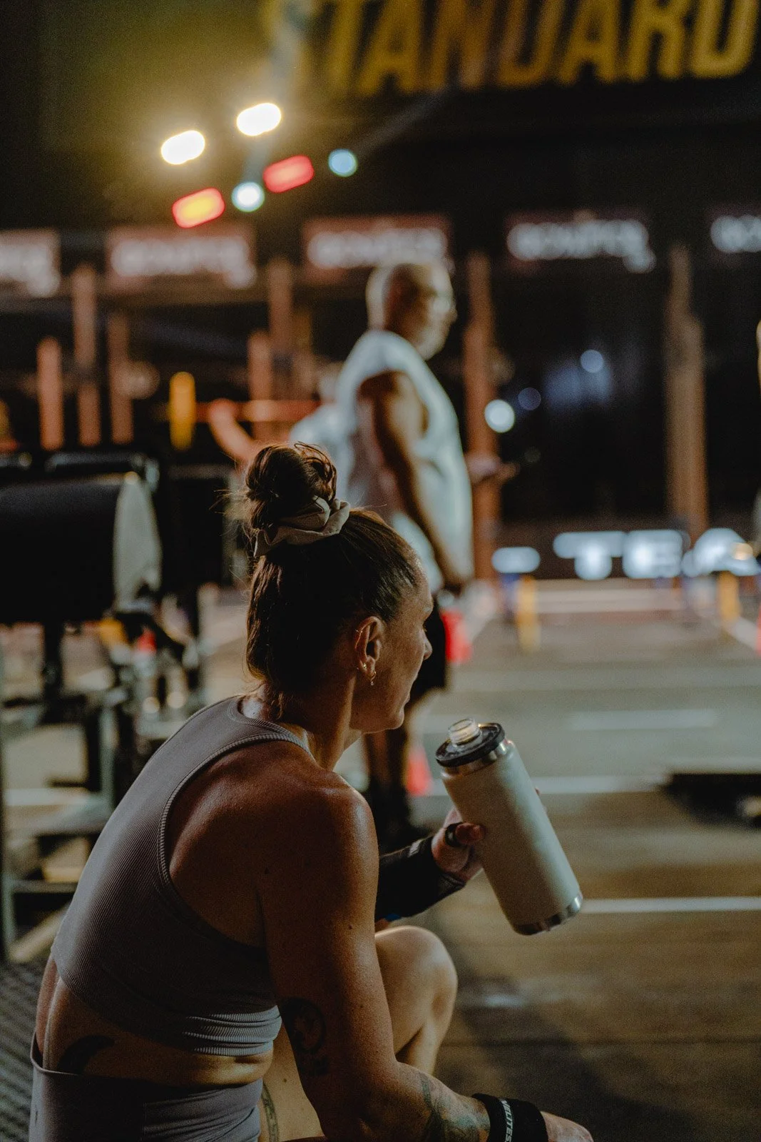 Athlète féminine s'hydratant dans une salle de sport pendant un entraînement nocturne à Chicago — photographe fitness Voar by Tim