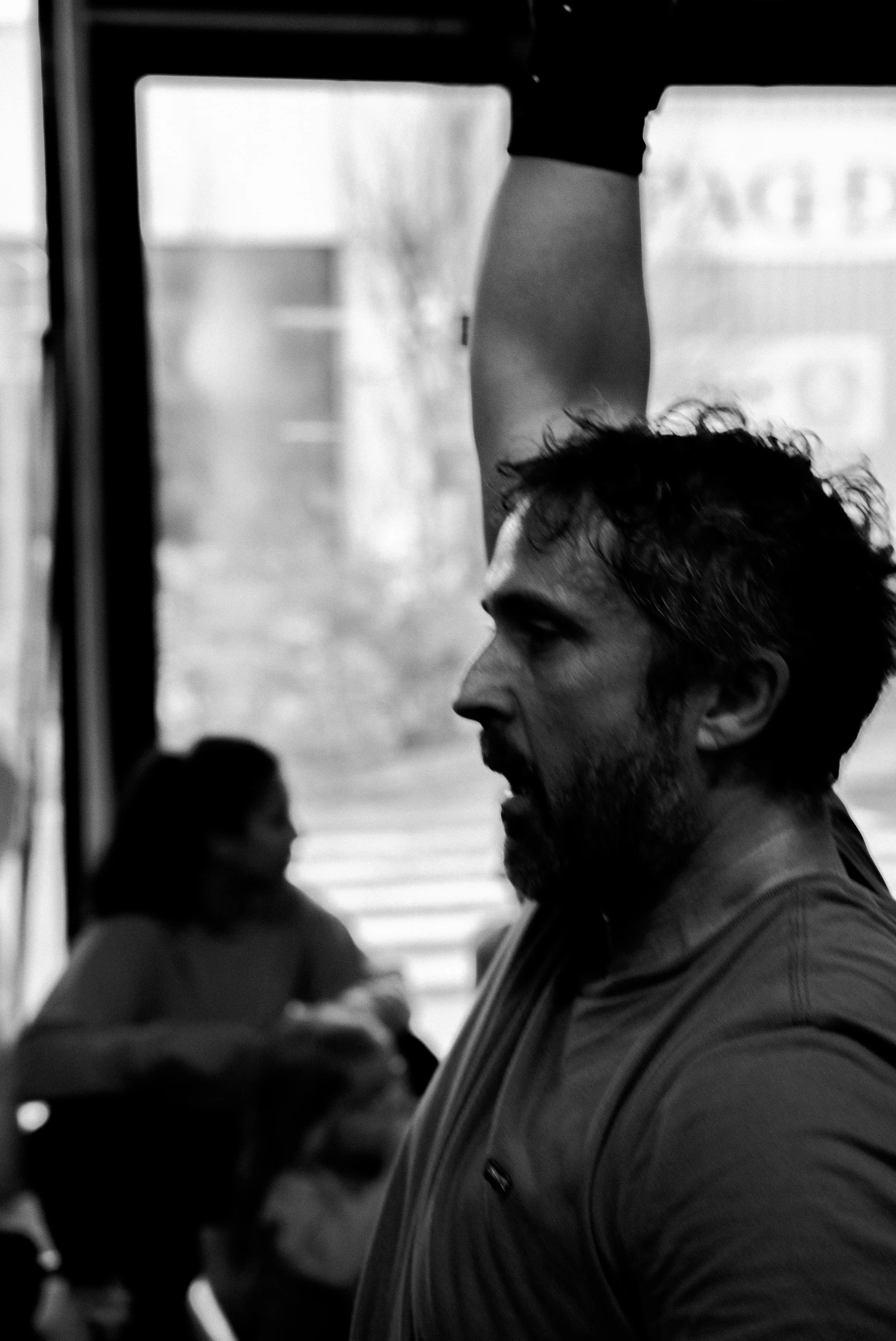 Un homme avec une barbe et cheveux bouclés qui regarde de côté dans un environnement intérieur.