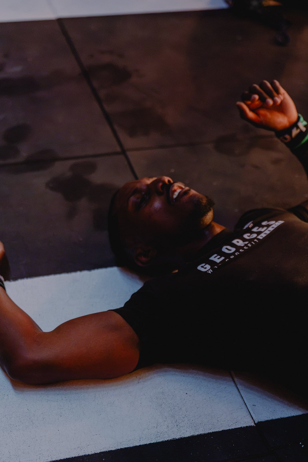 Homme souriant allongé au sol effectuant des exercices de musculation lors d'une séance CrossFit à Bordeaux — photographe CrossFit Voar by Tim