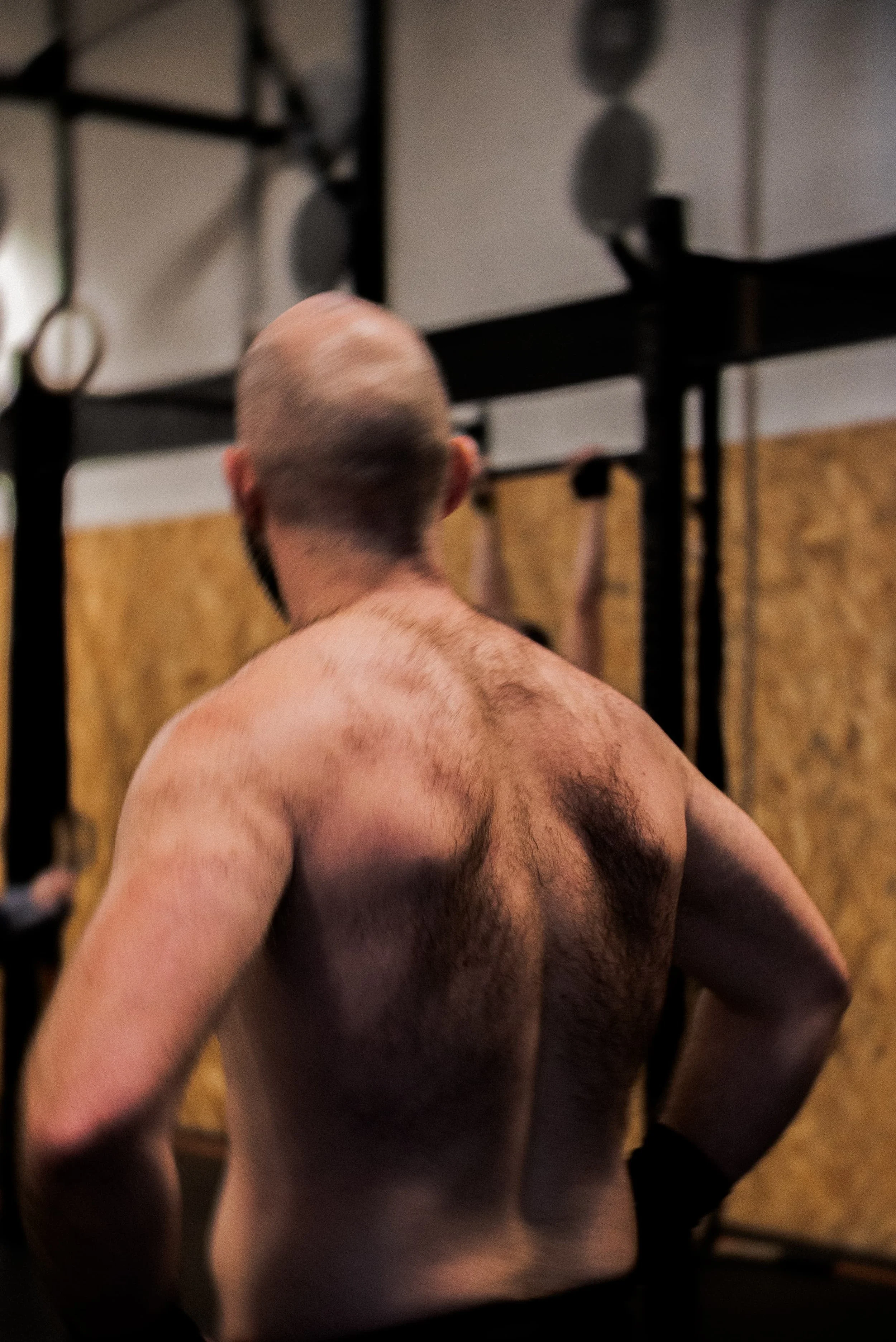 Un homme nu vu de derrière dans une salle de sport, faisant de l'exercice.