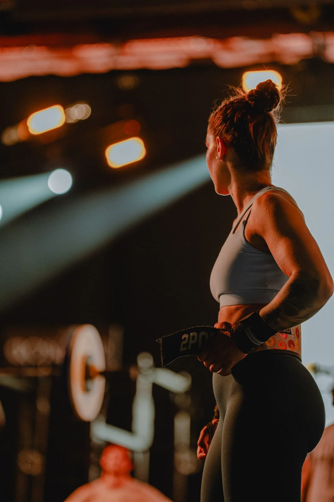 Athlète féminine vue de profil avec bande de résistance dans une salle de sport à Chicago, haut gris et pantalon noir — photographe fitness Voar by Tim