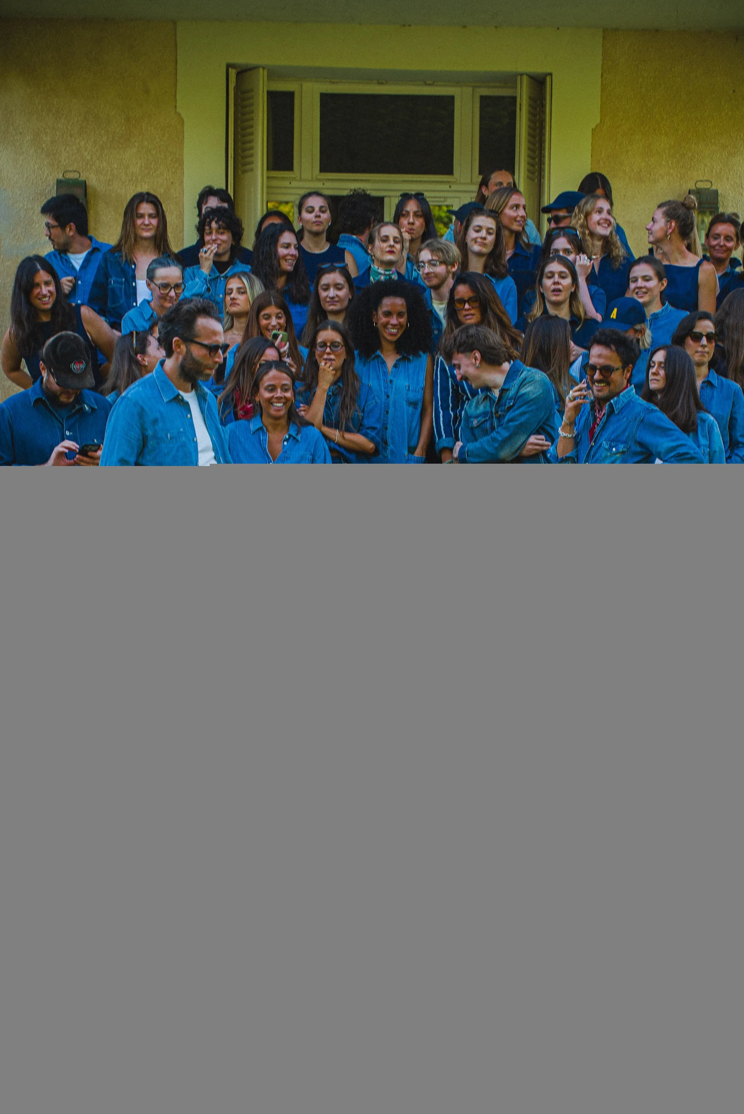 Groupe de personnes âgées portant des vêtements en jean, rieuses et souriantes, assistant à un événement."