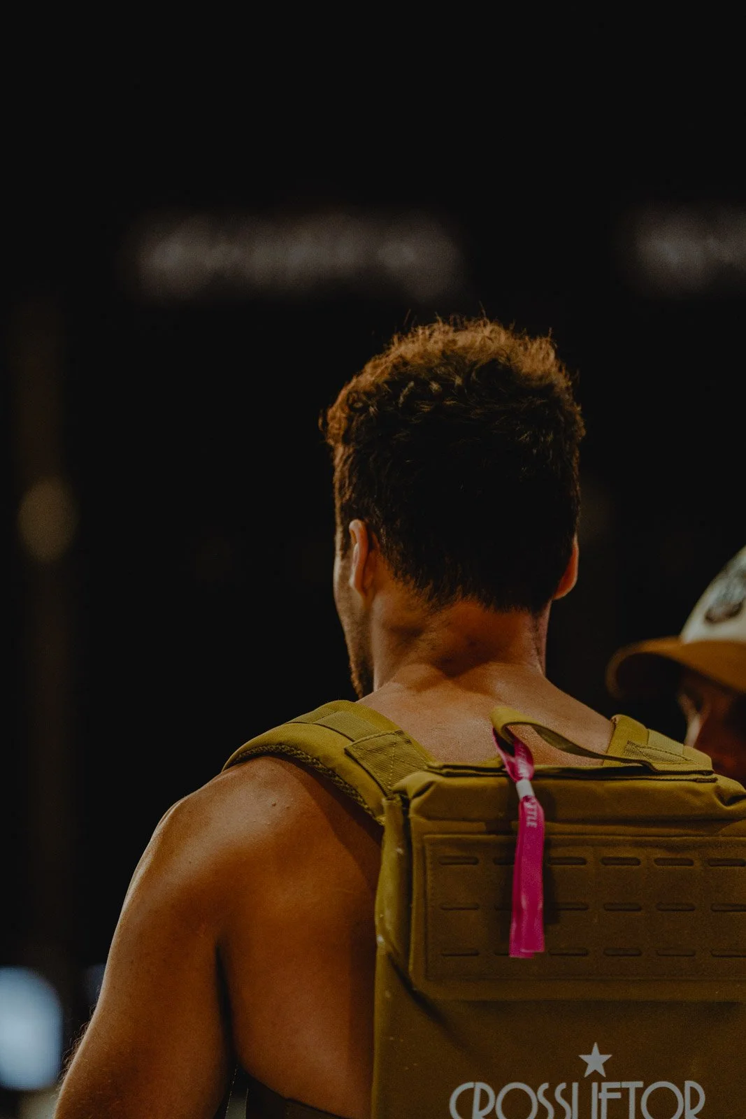 Homme de dos avec sac à dos kaki dans une salle CrossFit sombre à Bordeaux — photographe CrossFit Voar by Tim