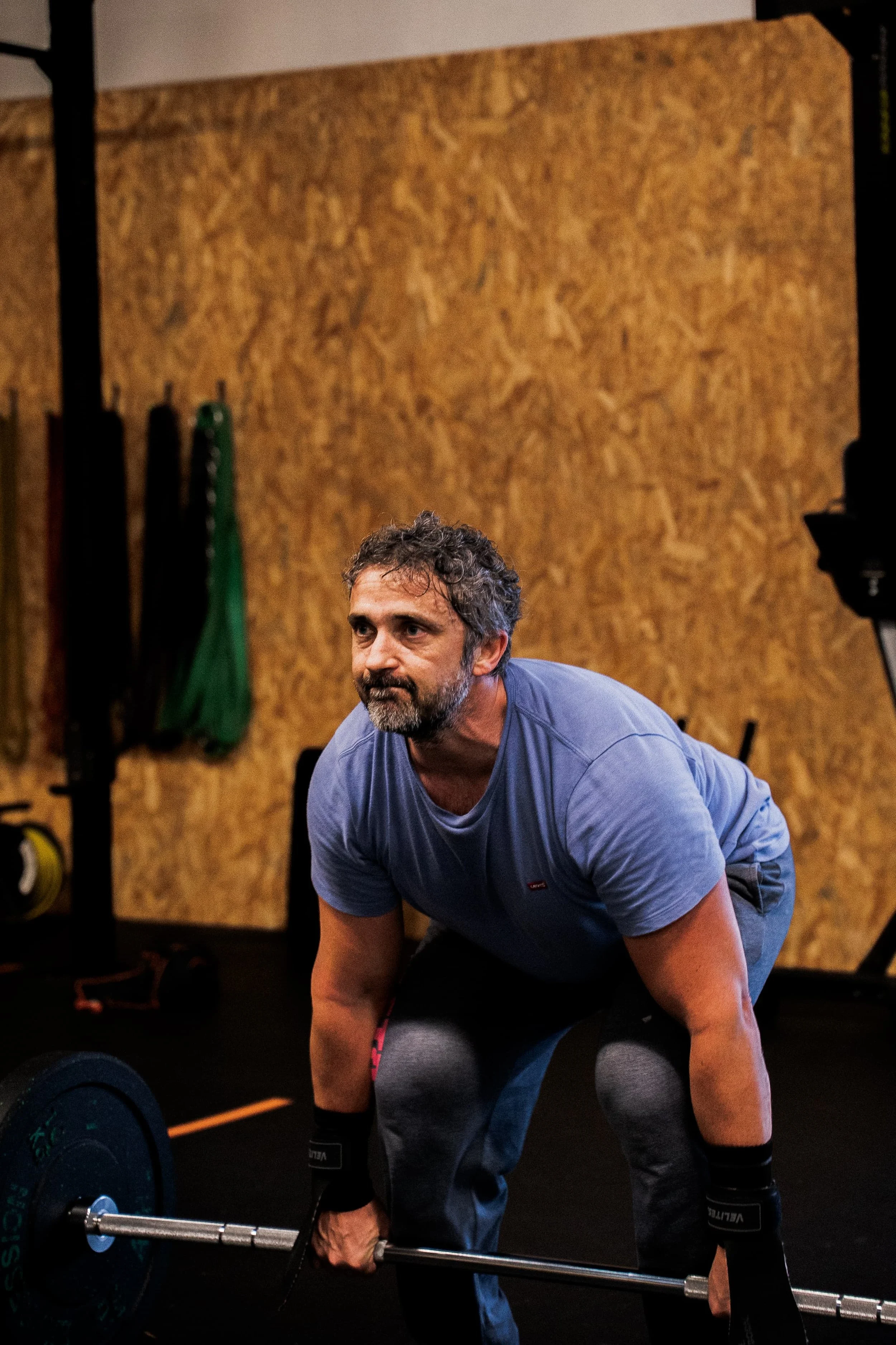 Un homme fait un entraînement de musculation dans une salle de sport, soulevant une barre avec des poids.