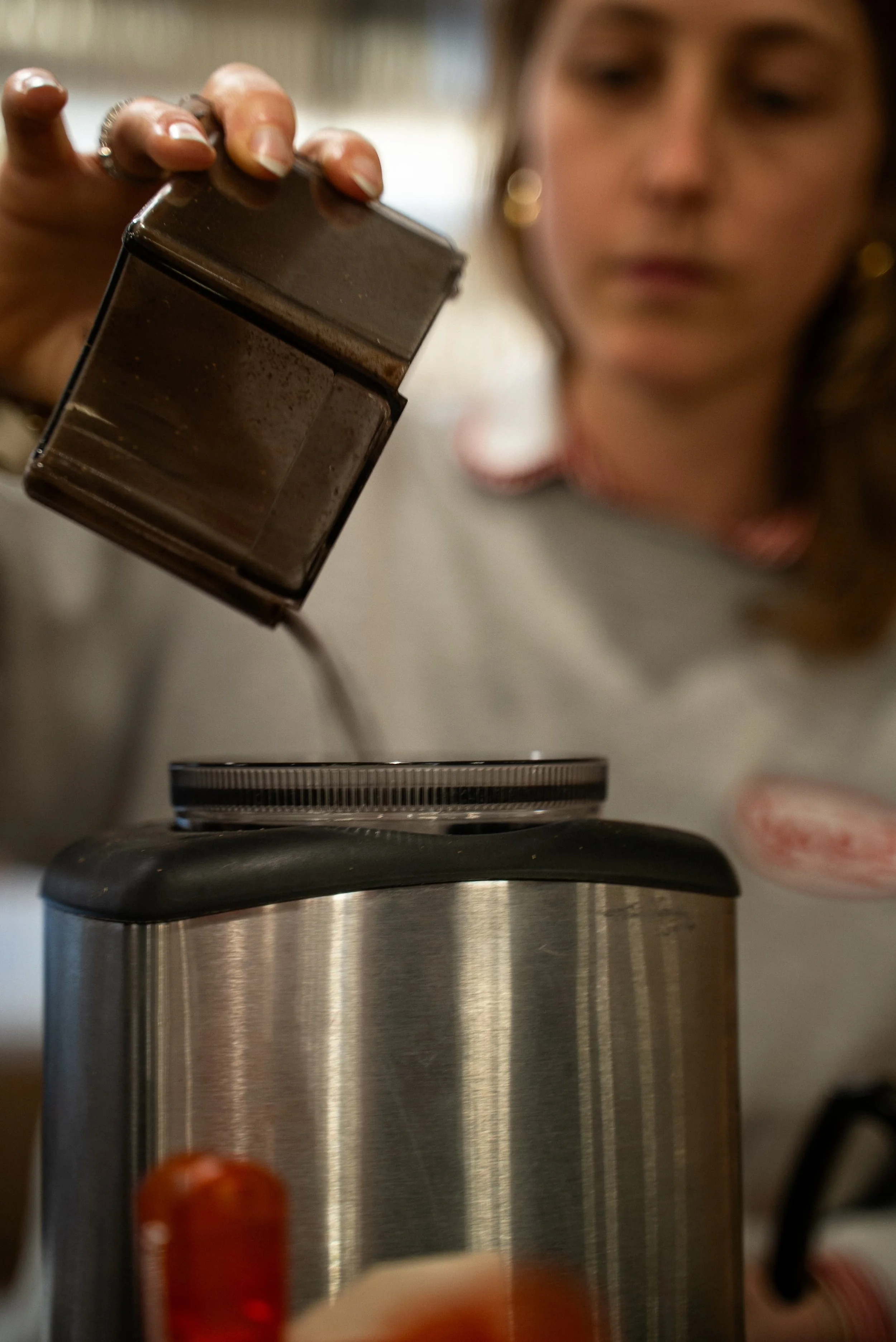 Une femme utilise une râpe électrique pour râper du chocolat dans une cuisine.