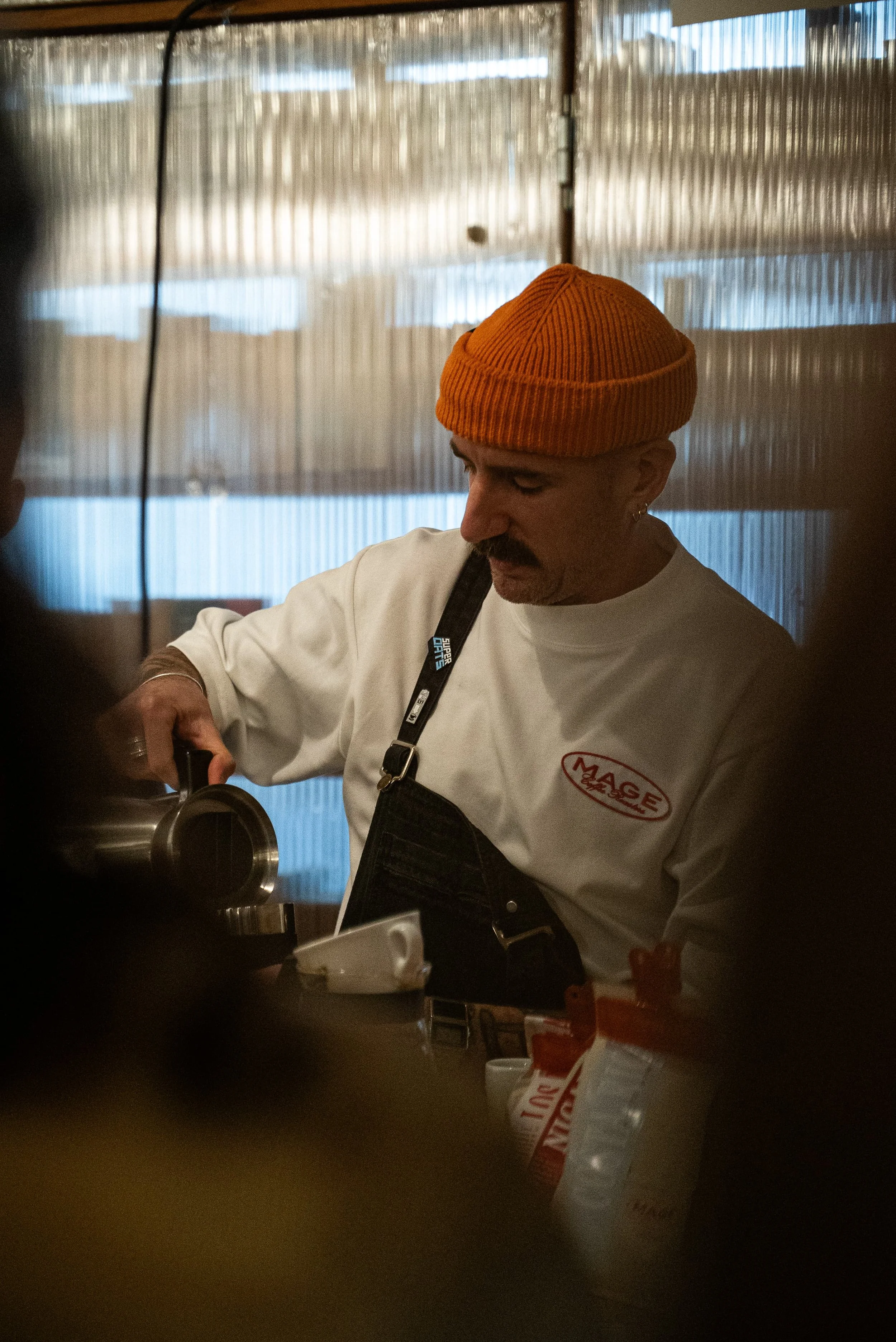 Un homme portant un bonnet orange, une chemise blanche avec un logo 