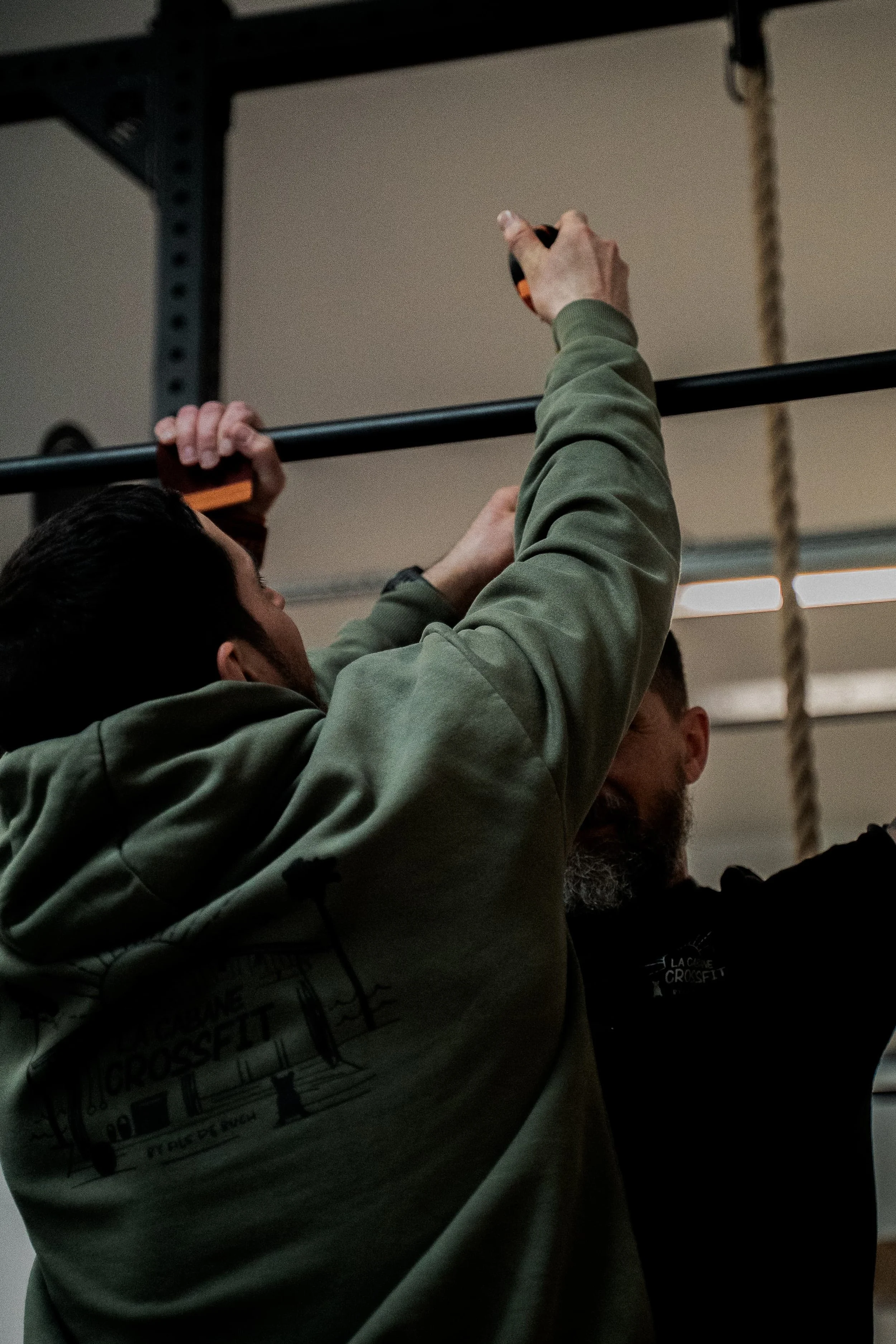 Hommes en train de faire des tractions à la barre dans une salle de sport.