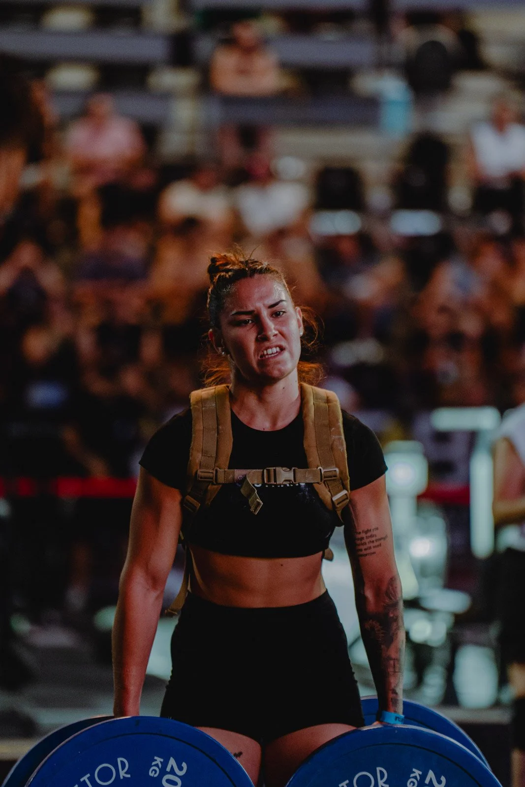 Athlète féminine épuisée avec sac à dos et poids lors d'une compétition fitness devant un public — photographe fitness Voar by Tim