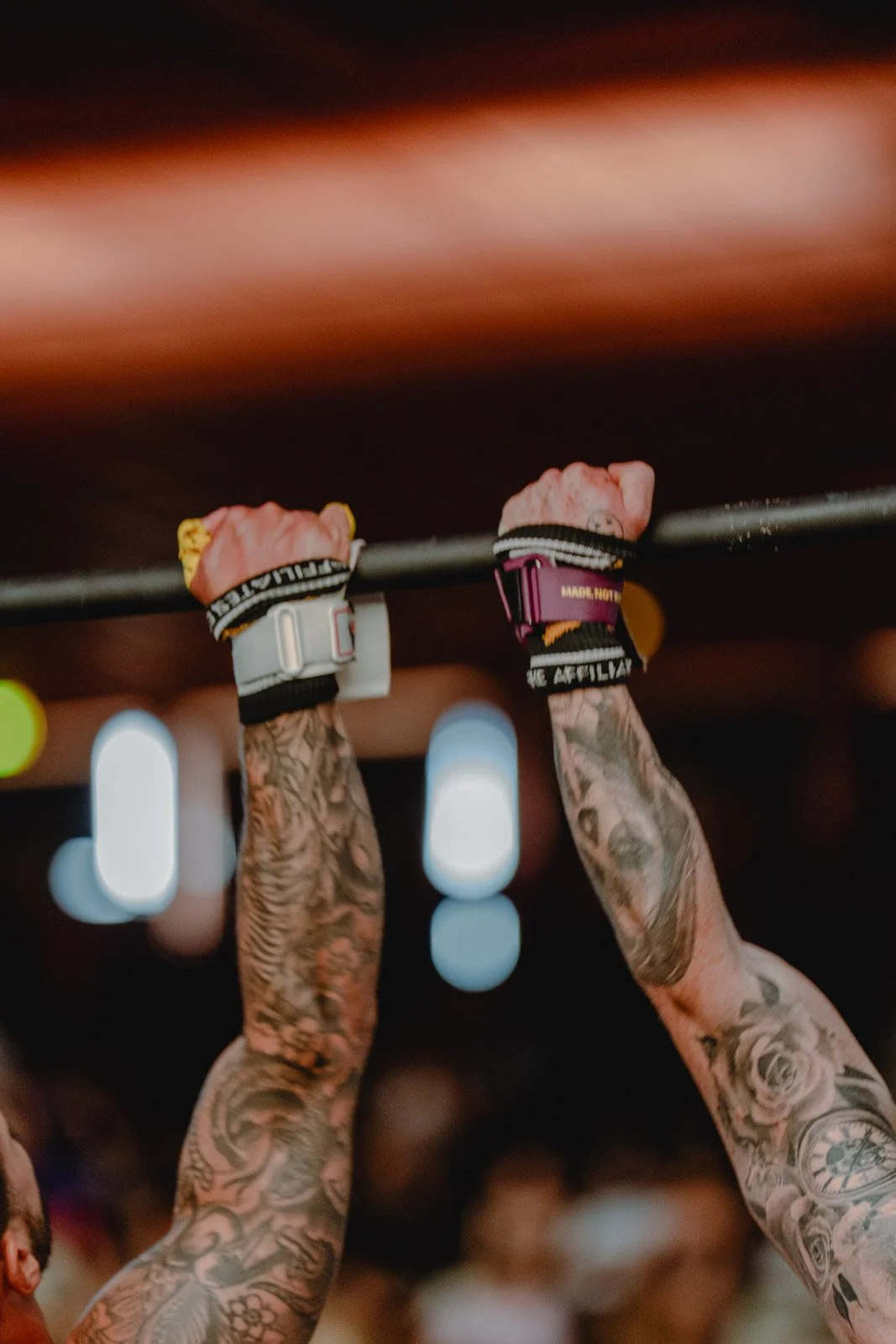 Athlètes soulevant une barre de traction avec tatouages et montres de sport lors d'une compétition CrossFit — photographe CrossFit Voar by Tim