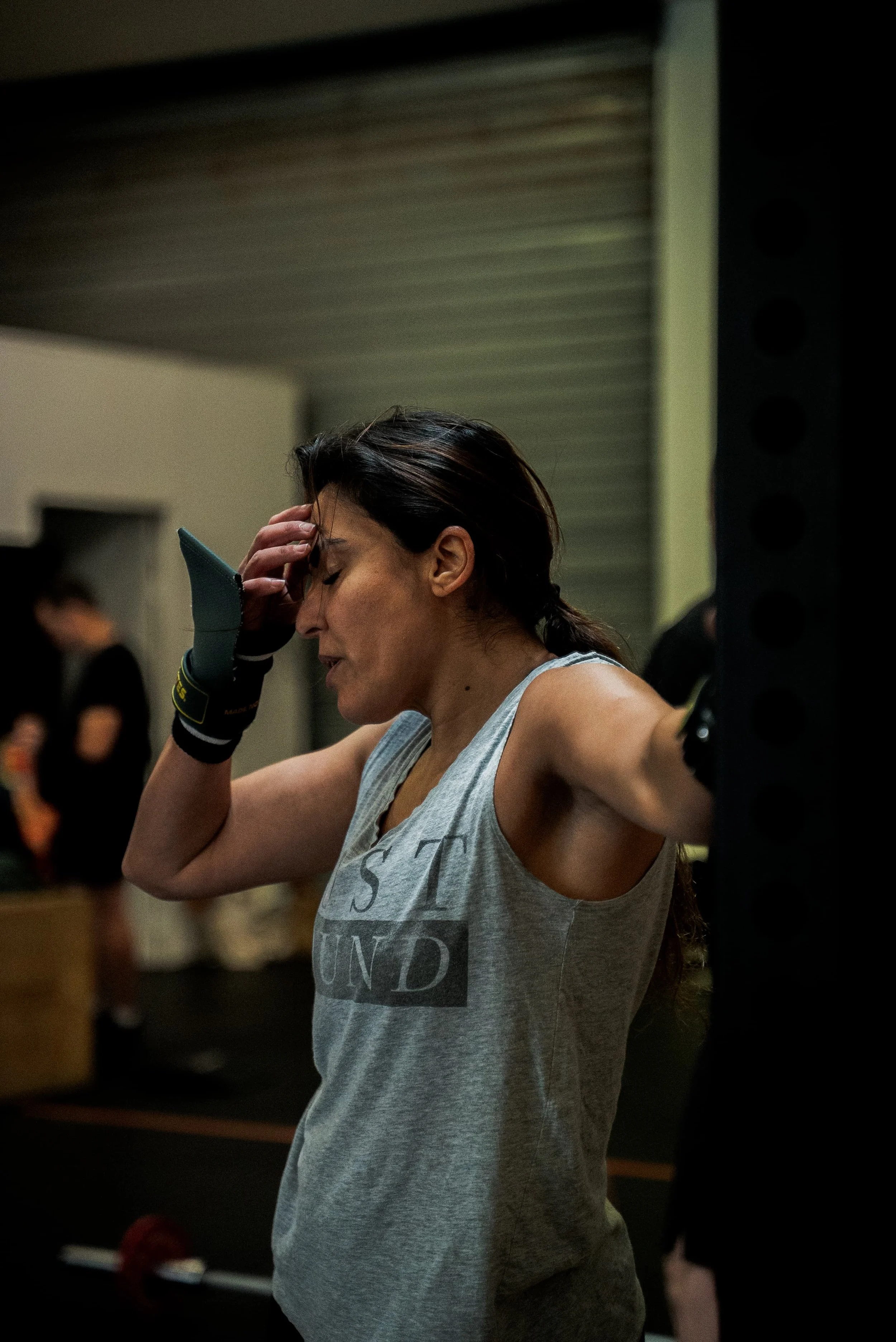 Une femme en tenue d'entraînement, en train de récupérer après un effort physique intense, dans un gymnase.