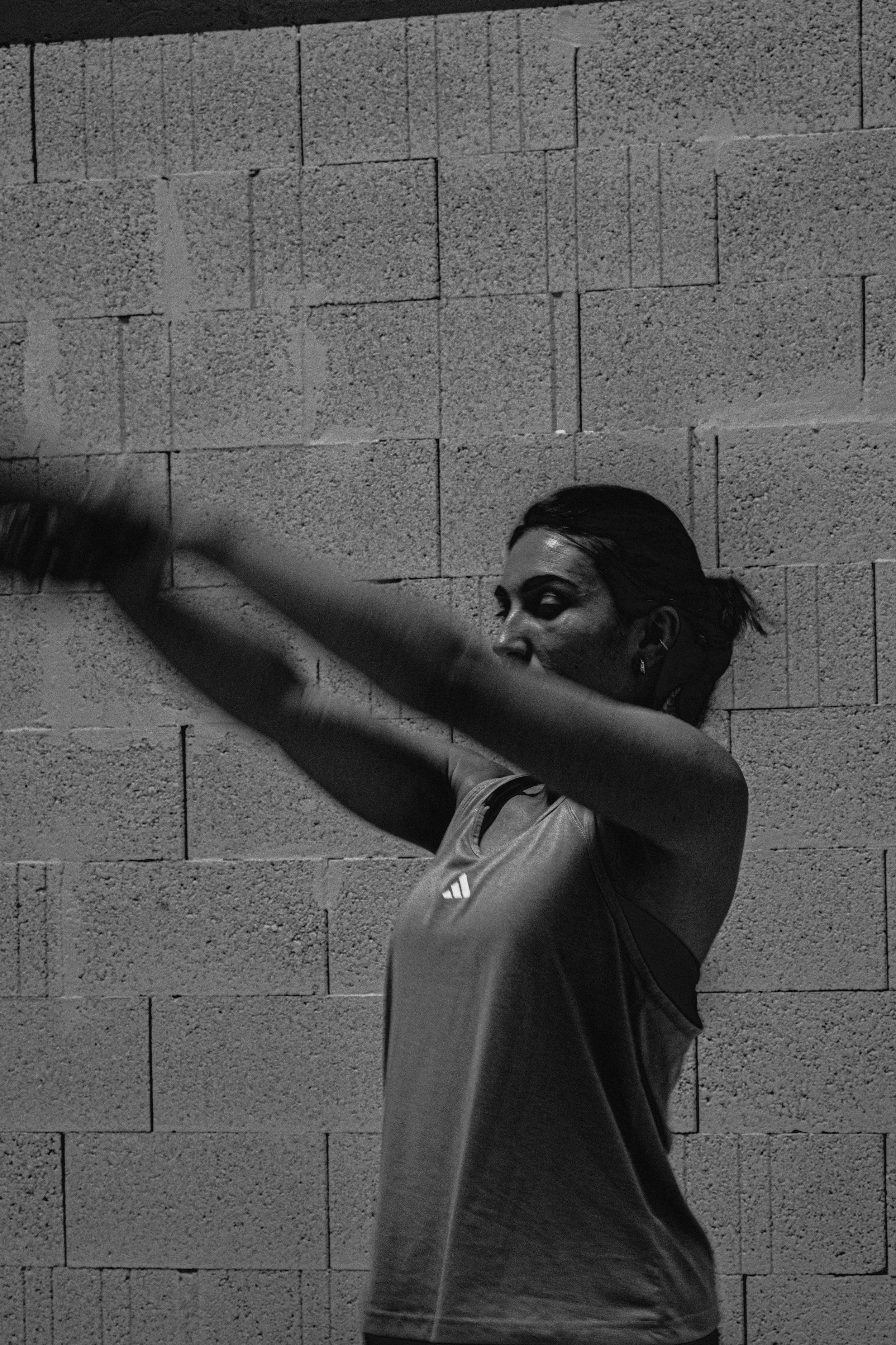 Une femme en tenue d'entraînement s'exerce contre un mur en briques.