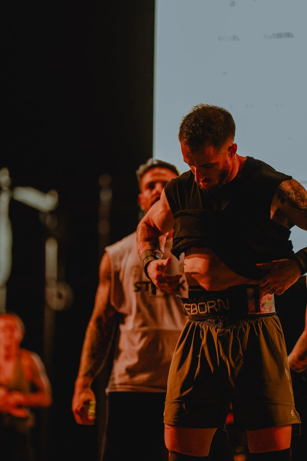 Sportif ajustant sa tenue avant une compétition CrossFit dans une salle sombre à Bordeaux — photographe CrossFit Voar by Tim