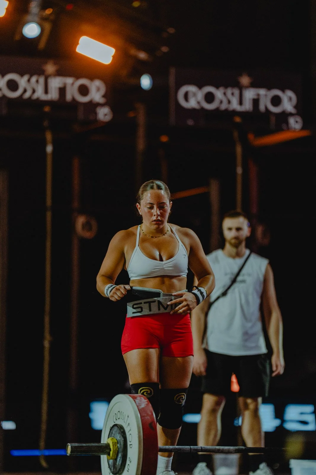 Femme préparant une barre de musculation lors d'une compétition CrossFit dans une salle sombre en Nouvelle-Aquitaine — photographe CrossFit Voar by Tim