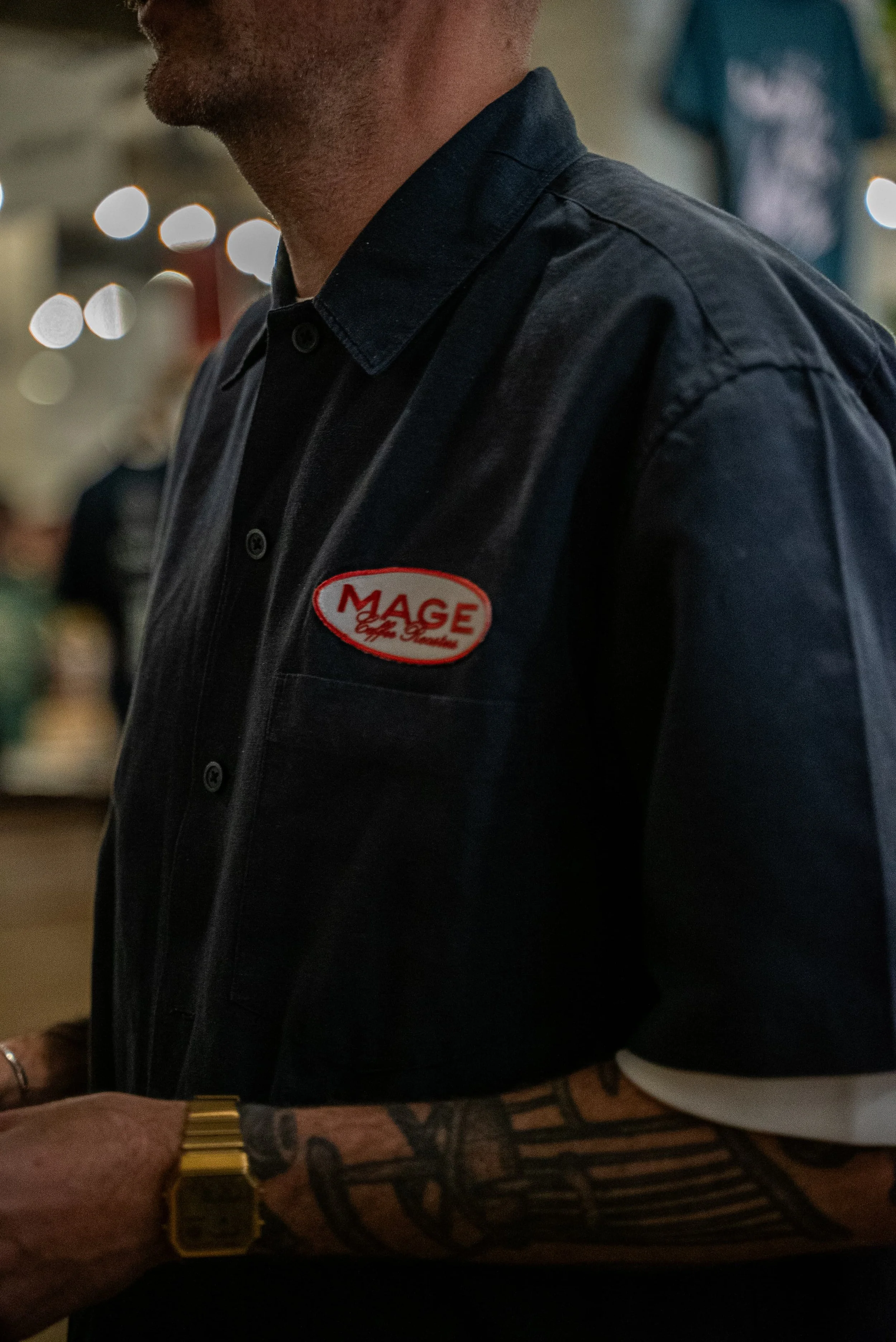 Une personne portant une veste noire avec un badge rouge et blanc marqué "MAGE".