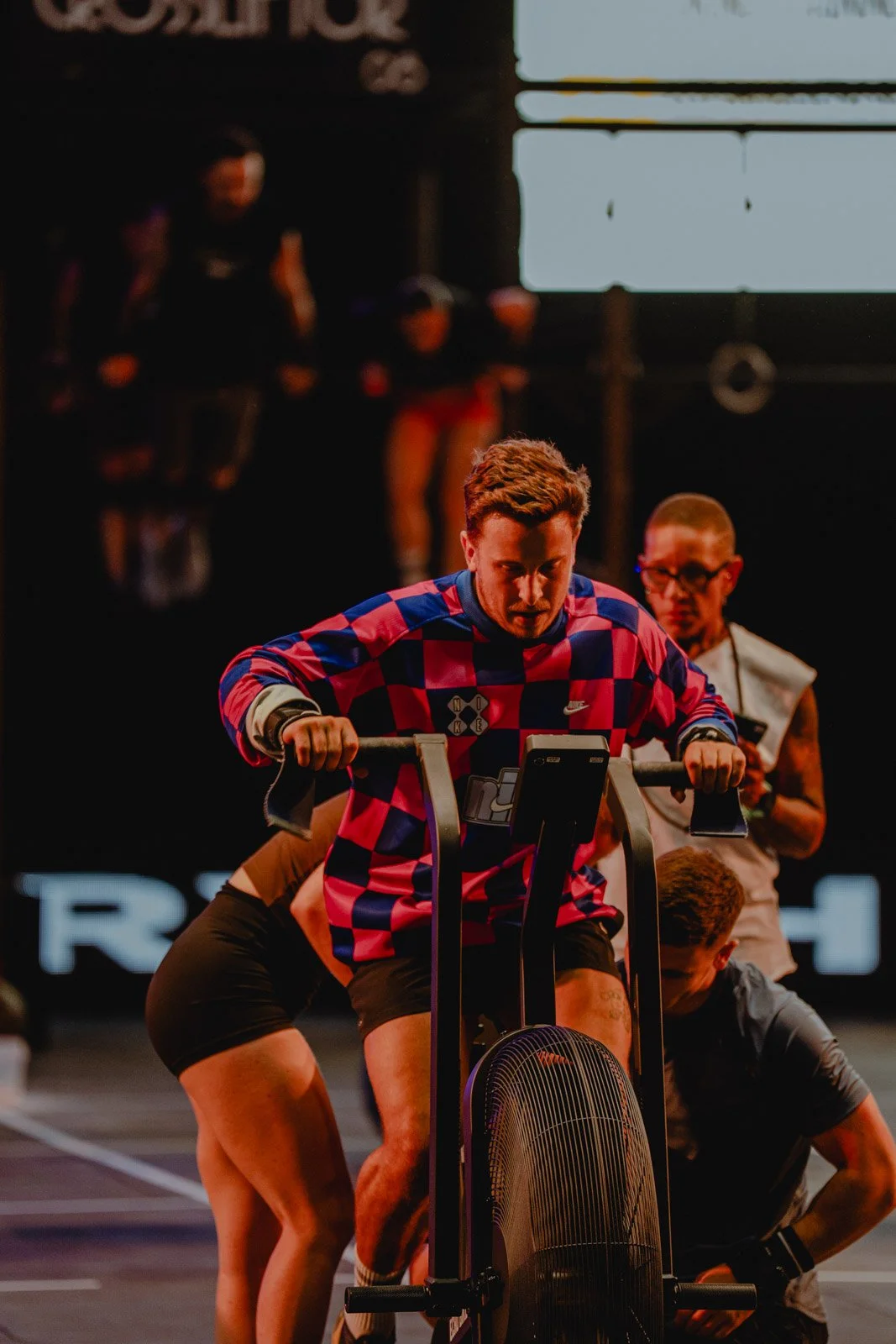 Homme poussant un vélo d'appartement lors d'une compétition CrossFit dans une salle sombre à Bordeaux — photographe CrossFit Voar by Tim