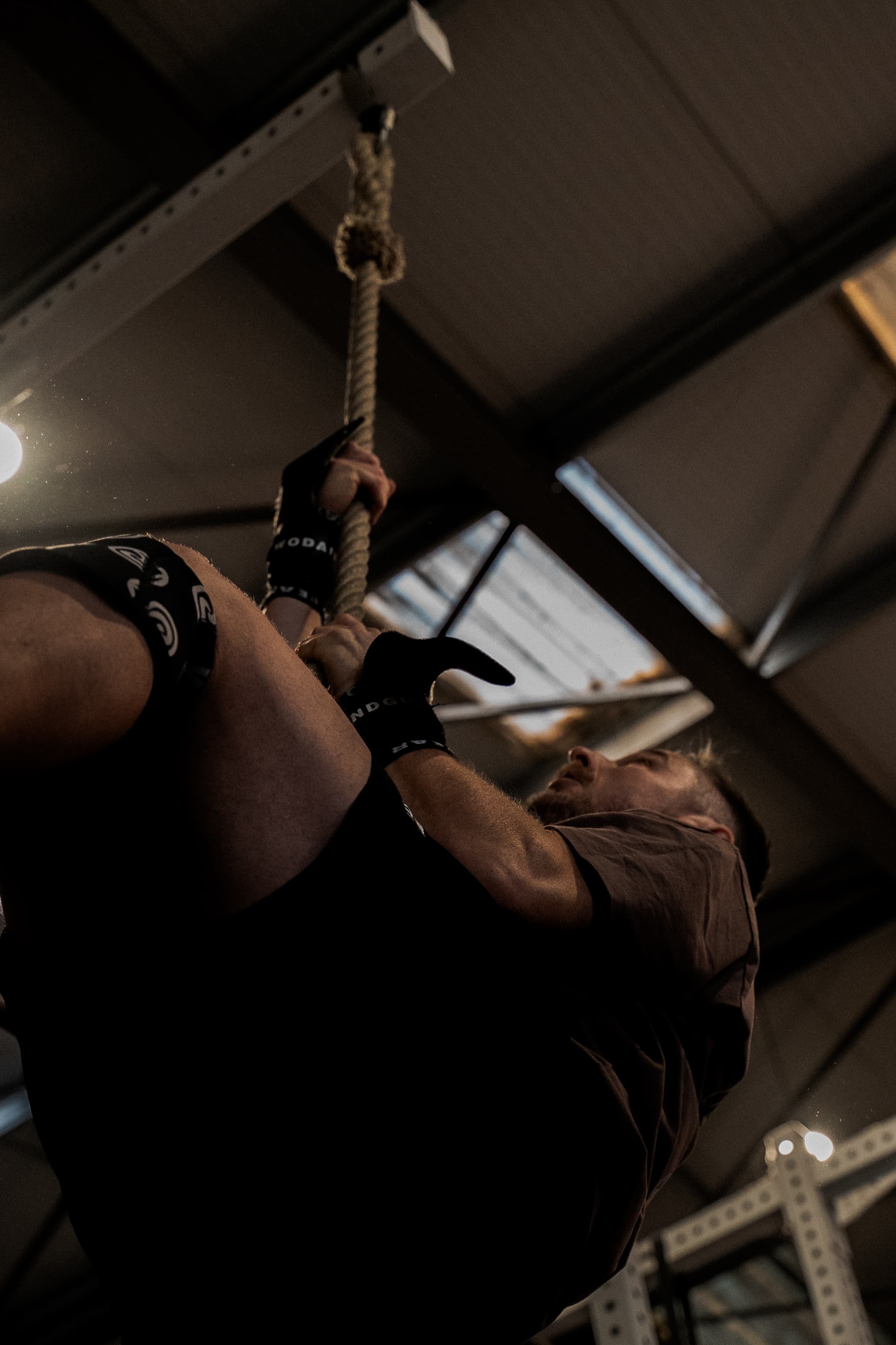 Personne tenant une corde dans un intérieur industriel sombre, probablement dans une salle de sport ou une salle d'entraînement.