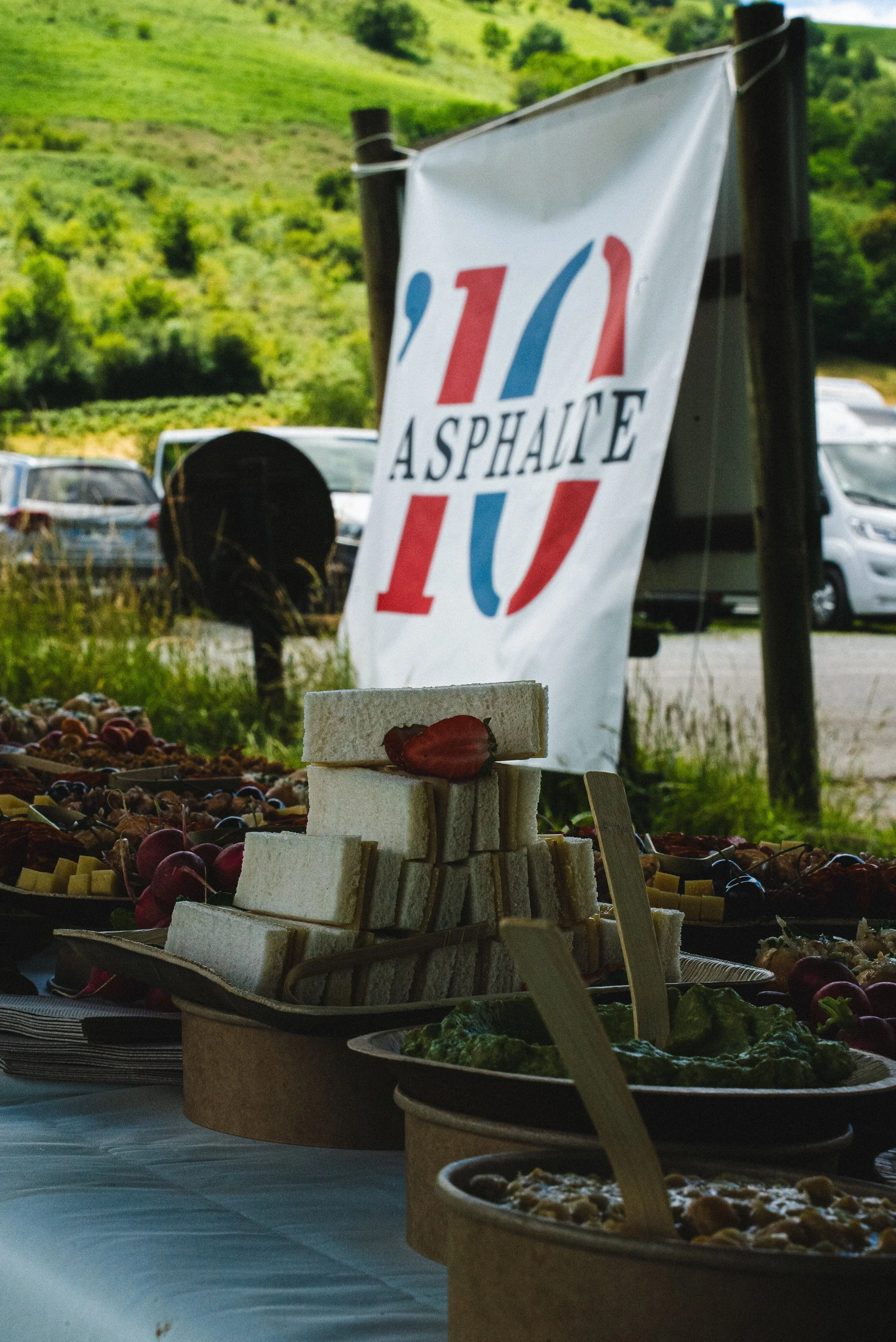 Un buffet de nourriture comprenant des sandwiches, des fruits, des dips et autres mets devant un drapeau français avec le texte 'À Sphaine'.