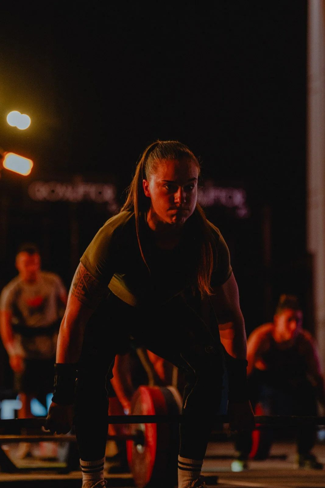 Femme soulevant une barre dans une salle de sport lors d'une séance nocturne CrossFit — photographe CrossFit Voar by Tim