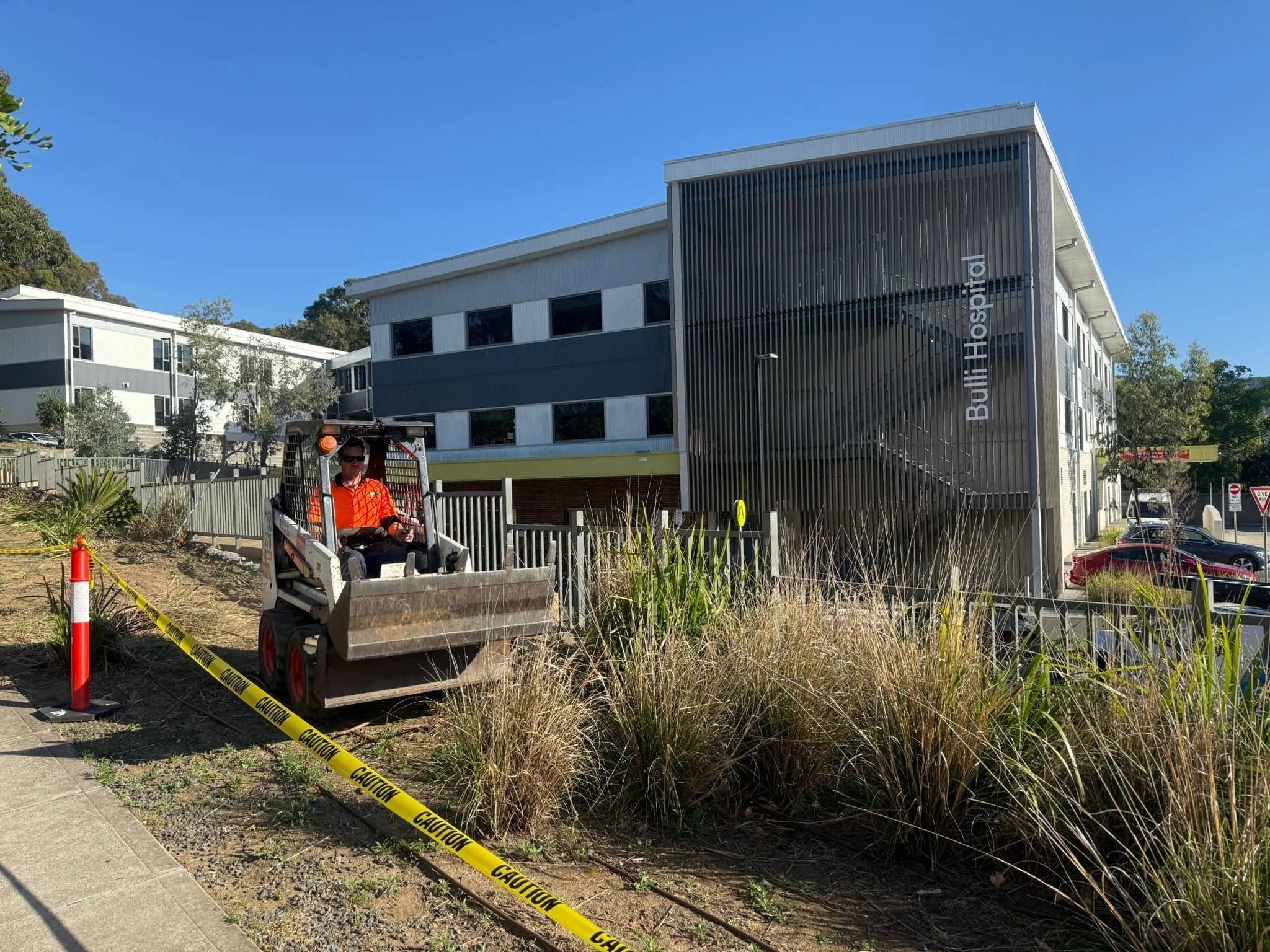 Worker operating construction equipment near a hospital site