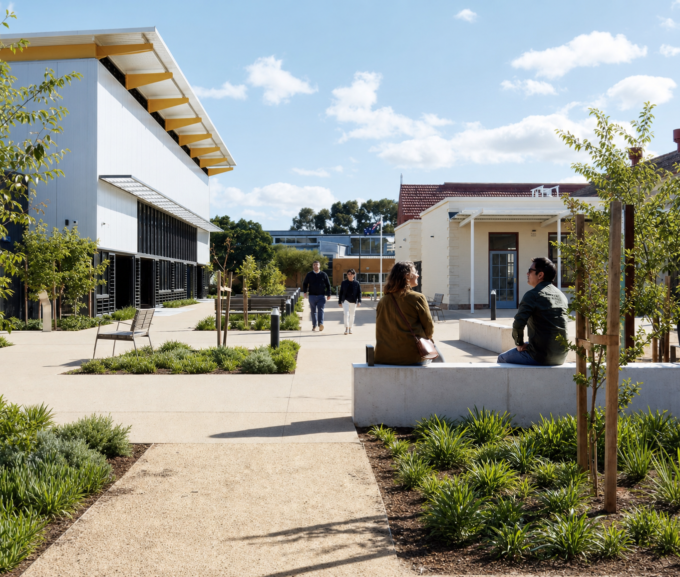 People sitting and walking in a sunny, landscaped outdoor area between modern and traditional buildings with trees and benches.