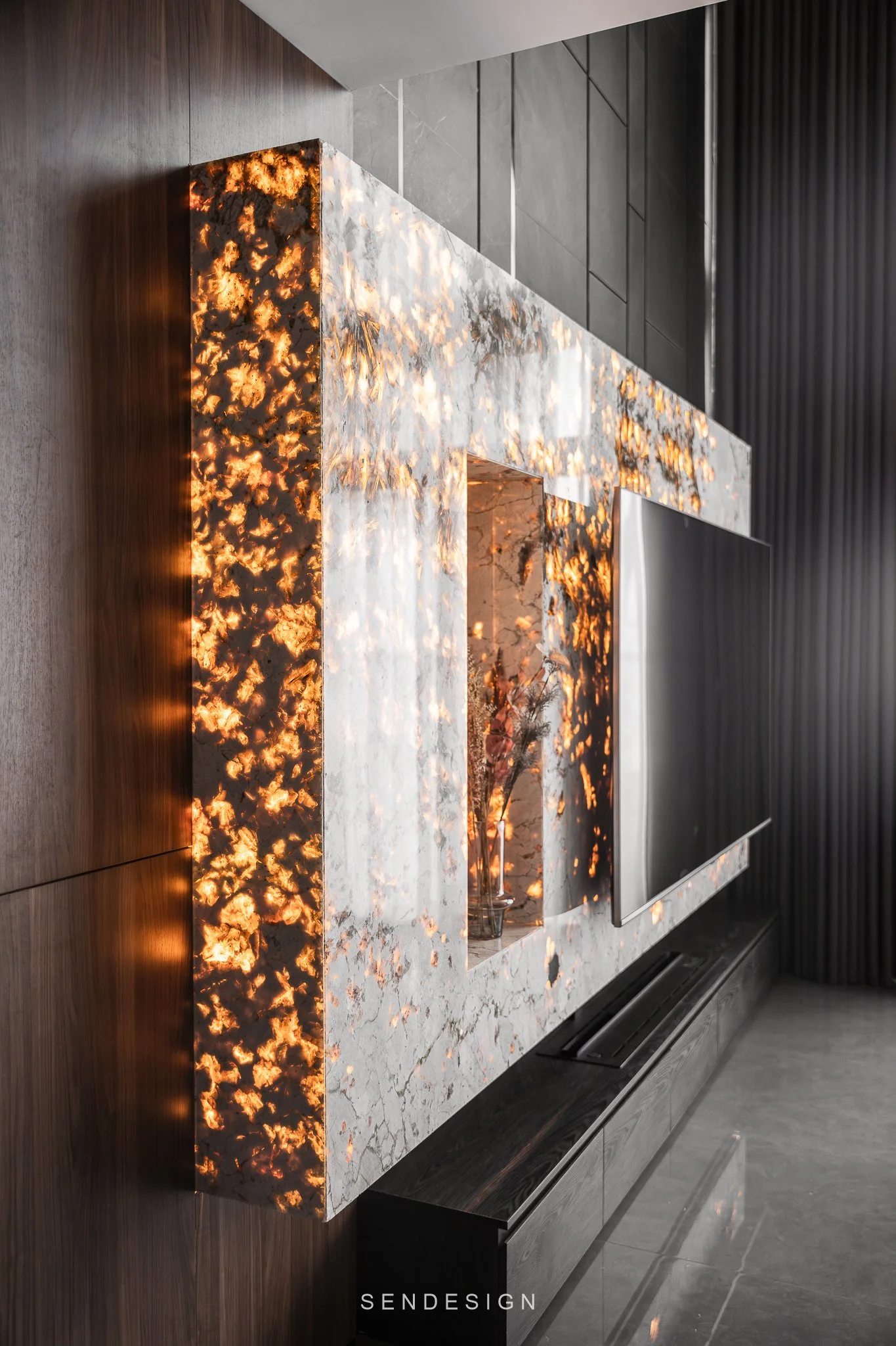 Modern interior fireplace with a marble surround and decorative black panels on the wall, with orange and yellow fire glow.