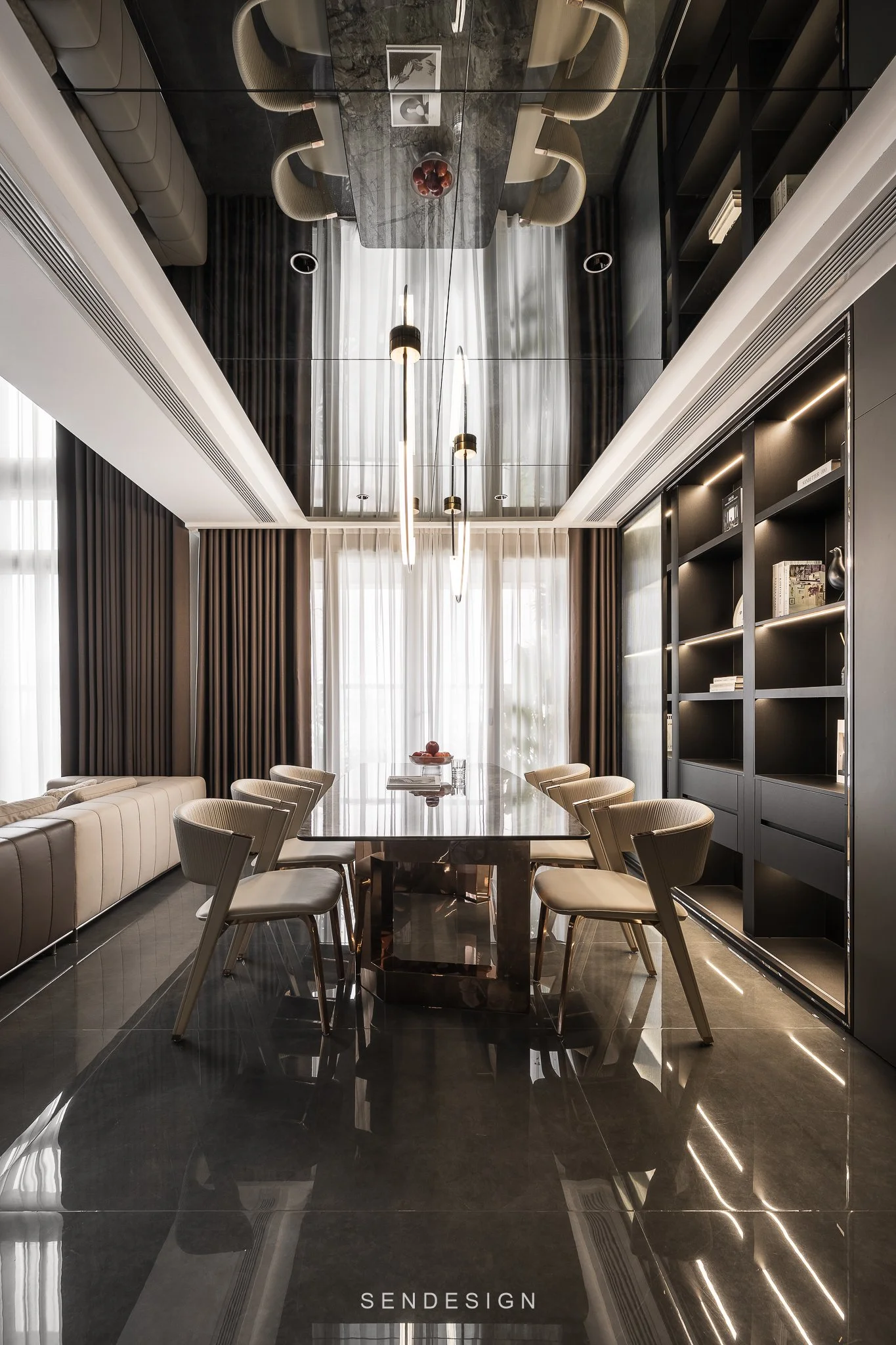 A modern dining room with a large rectangular marble dining table surrounded by beige chairs, a built-in black bookshelf, large windows with white curtains, dark hardwood floors, black paneled walls, and a mirrored ceiling with modern pendant lightin