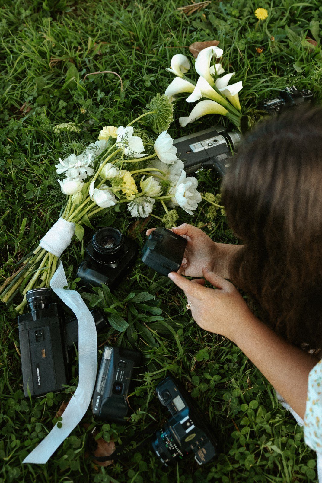 Robyn Small taking a photo of a floral arrangement with cameras on grass.