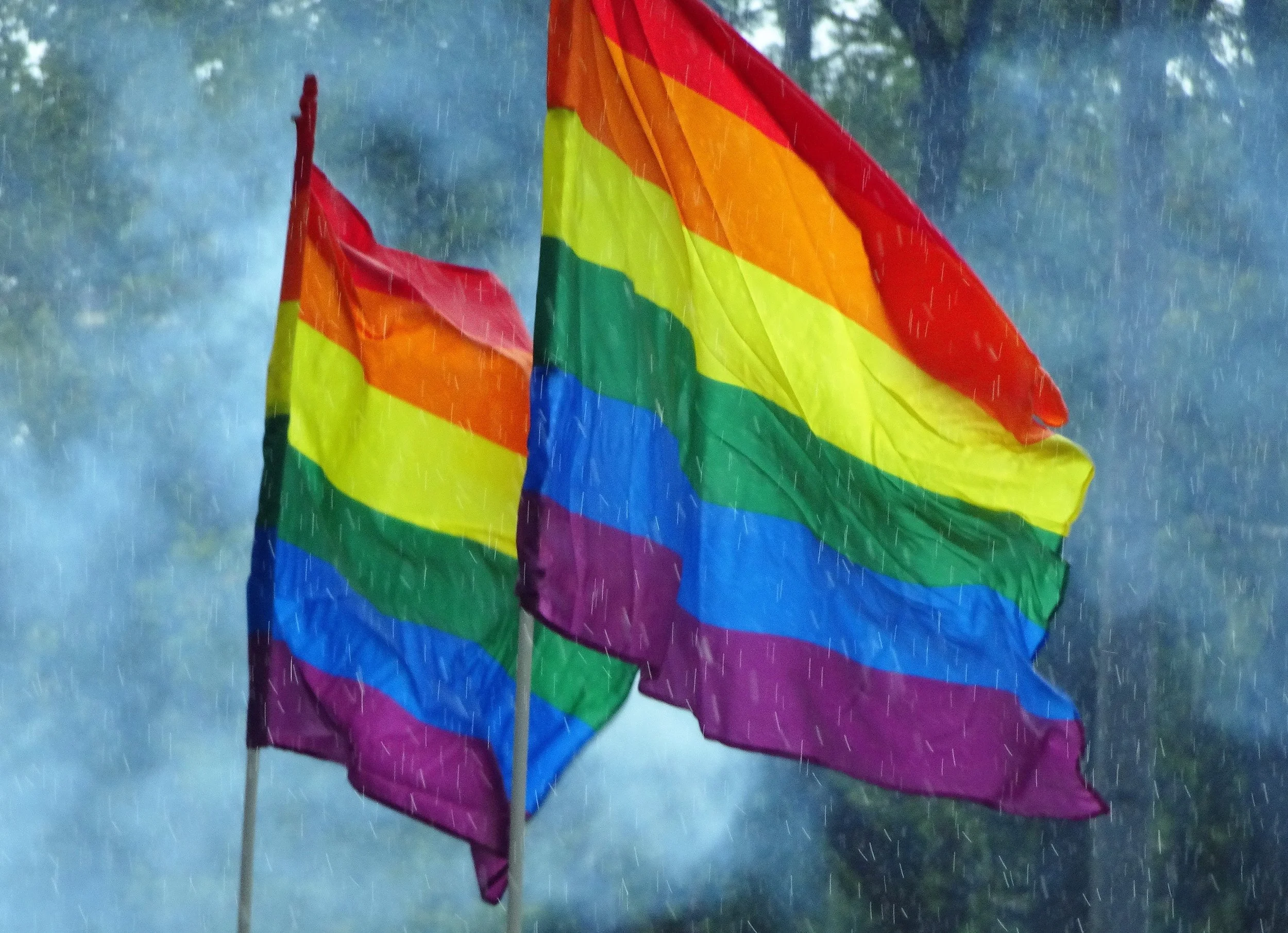 Colorful rainbow pride flag waving in the rain outdoors.