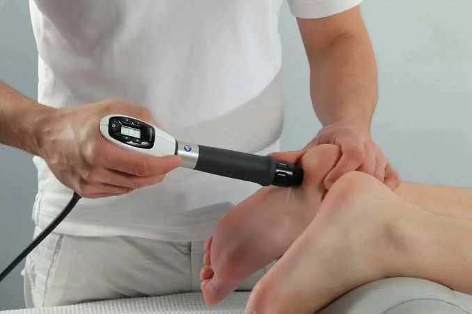 A healthcare professional using an ultrasound device on a patient's ankle during a medical examination.