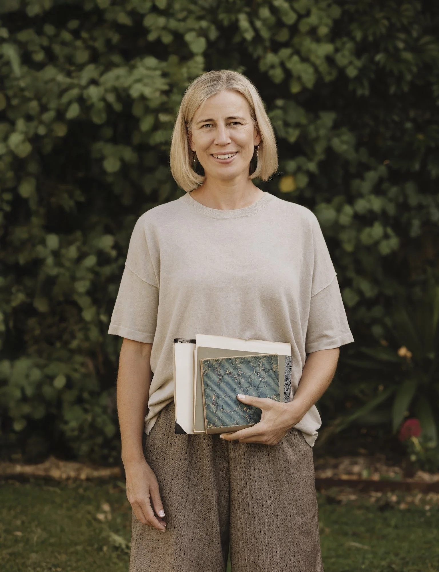 Nicky Scoltock, Green Sketching guide and Ambassador for Aotearoa New Zealand, holding her sketchbooks.