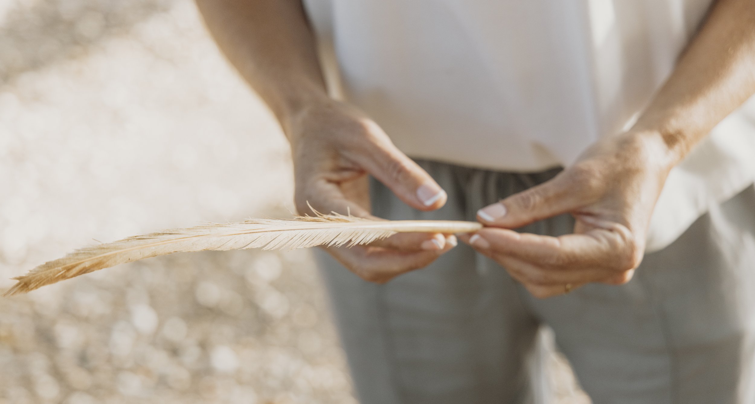 A person holding a feather with both hands.