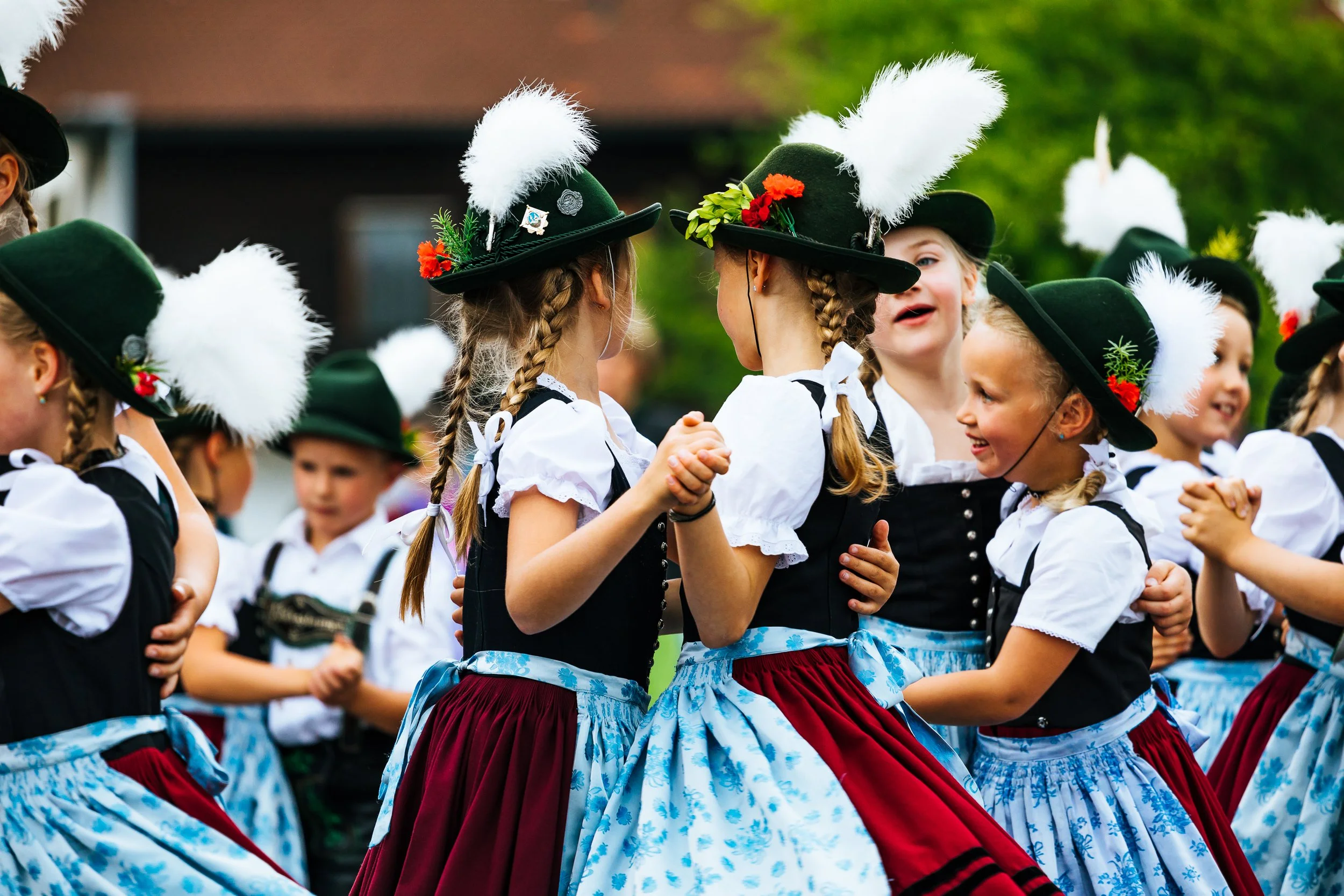 Mädchen in traditionellen bayerischen Trachten tanzen bei einem Fest.