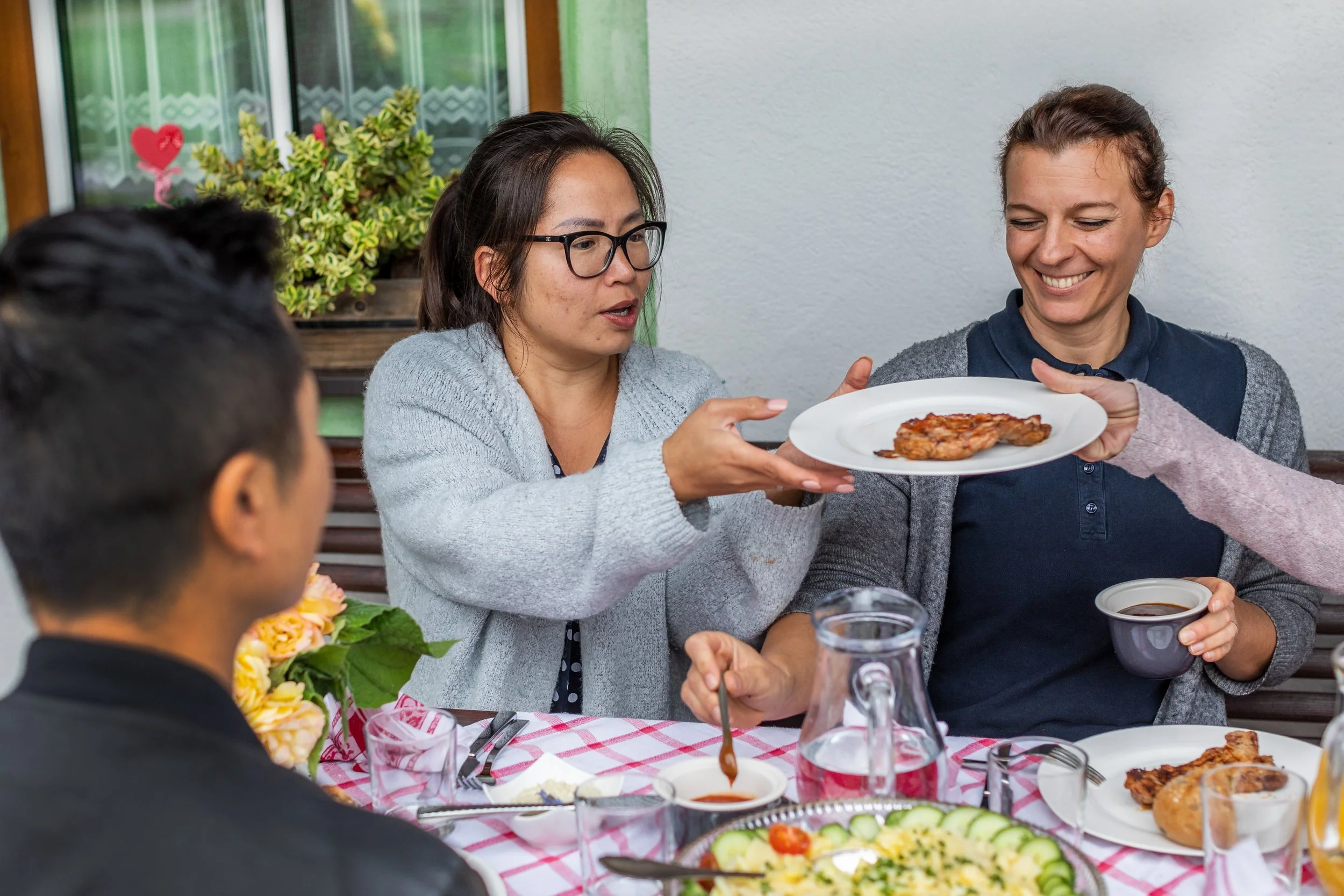 Frauen beim Essen und Austausch am Tisch im Garten.