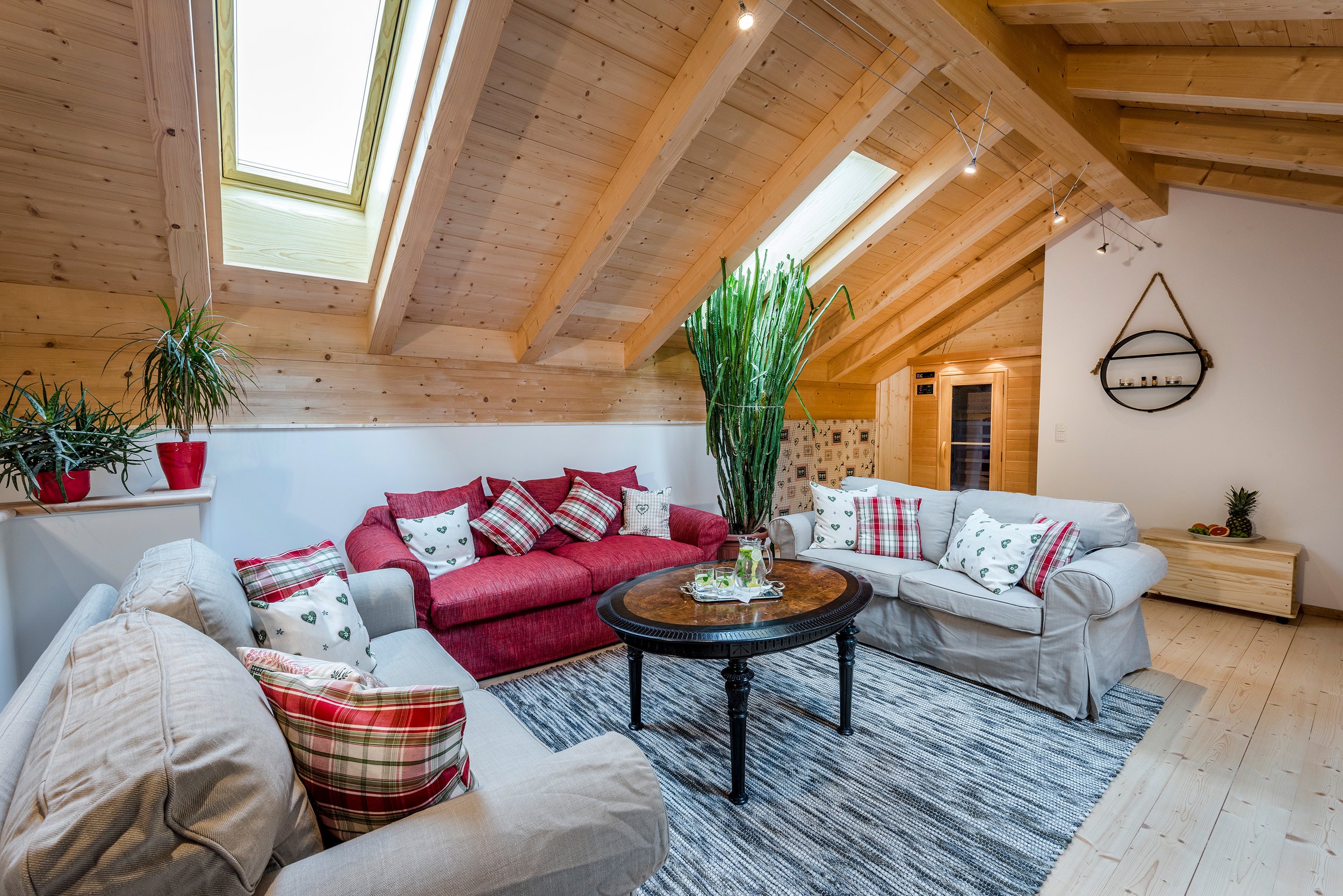 Gemütliches Wohnzimmer auf Galerie mit Holzdecke, Dachfenstern, Sofas, Pflanzen und rundem Couchtisch