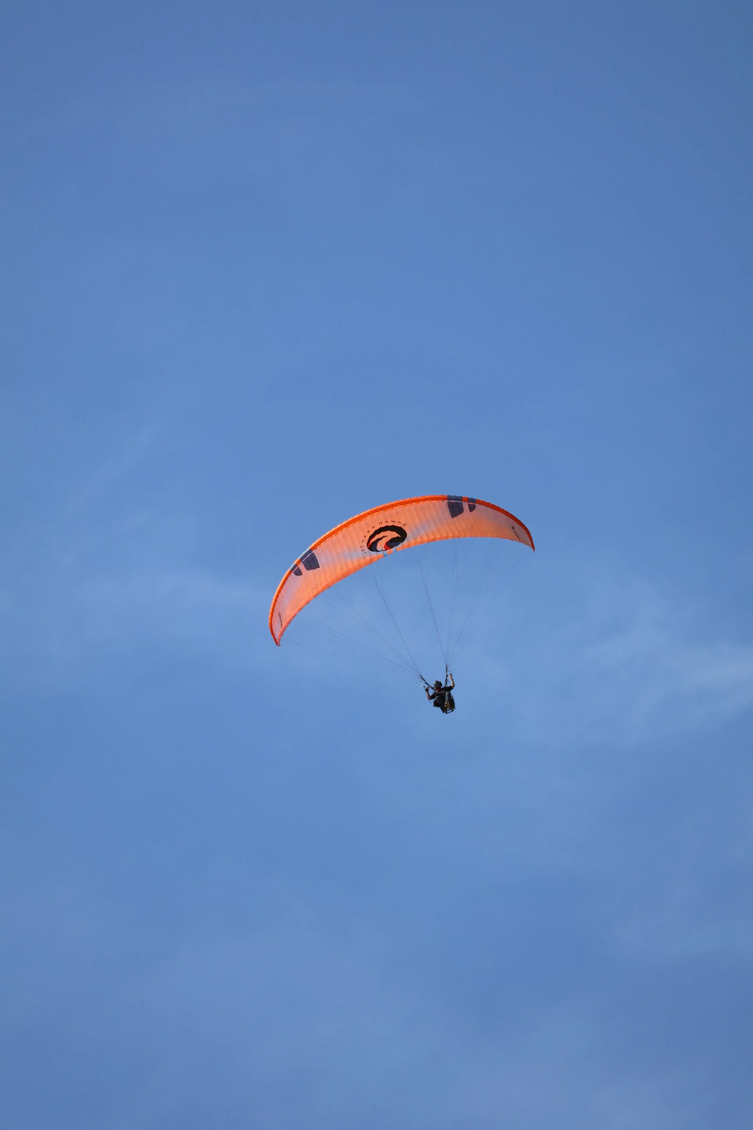 Paraglider flying in a clear blue sky.