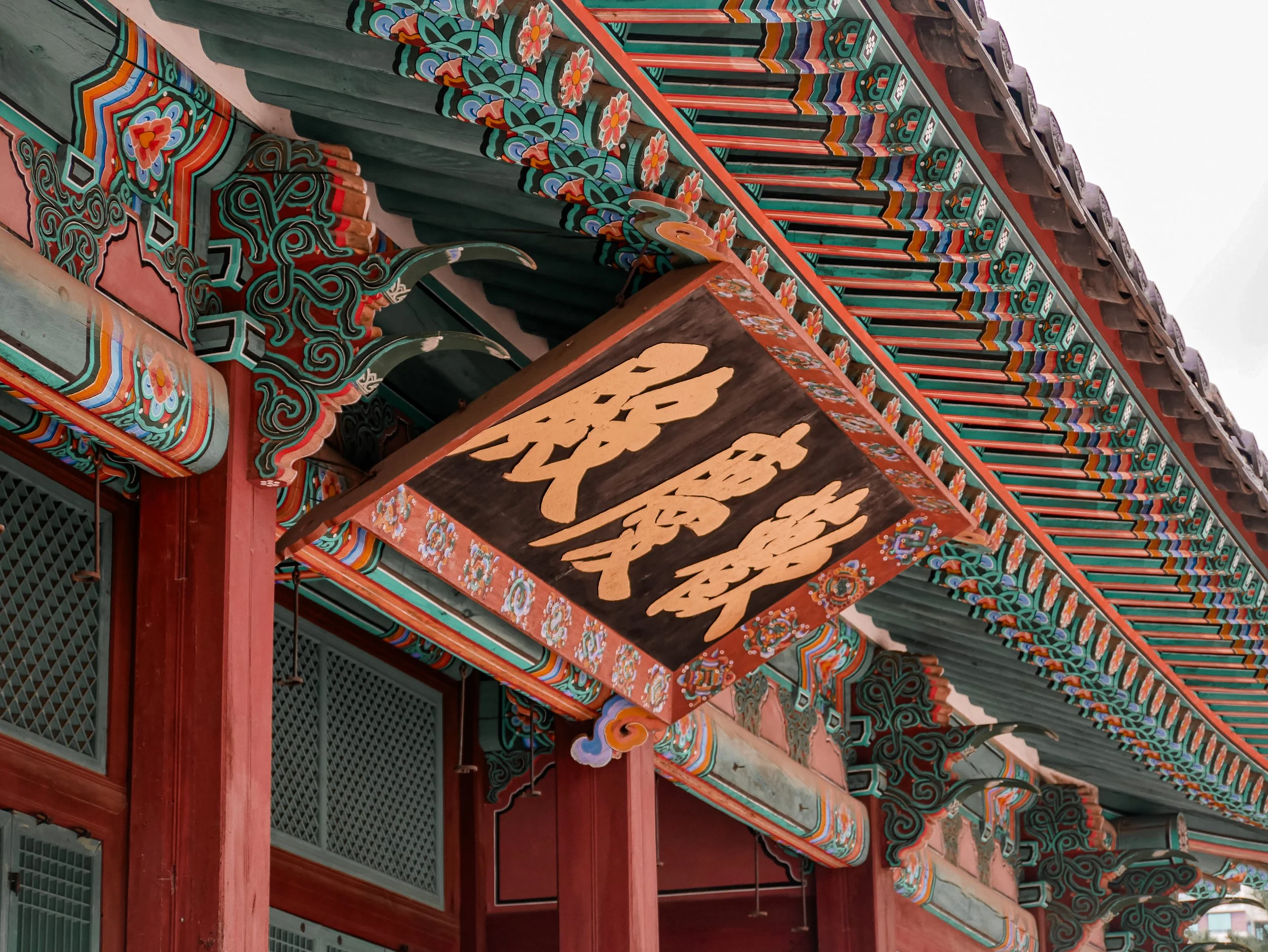 Close-up of colorful, ornate traditional East Asian architectural decoration on a building, featuring intricate patterns and vibrant colors.