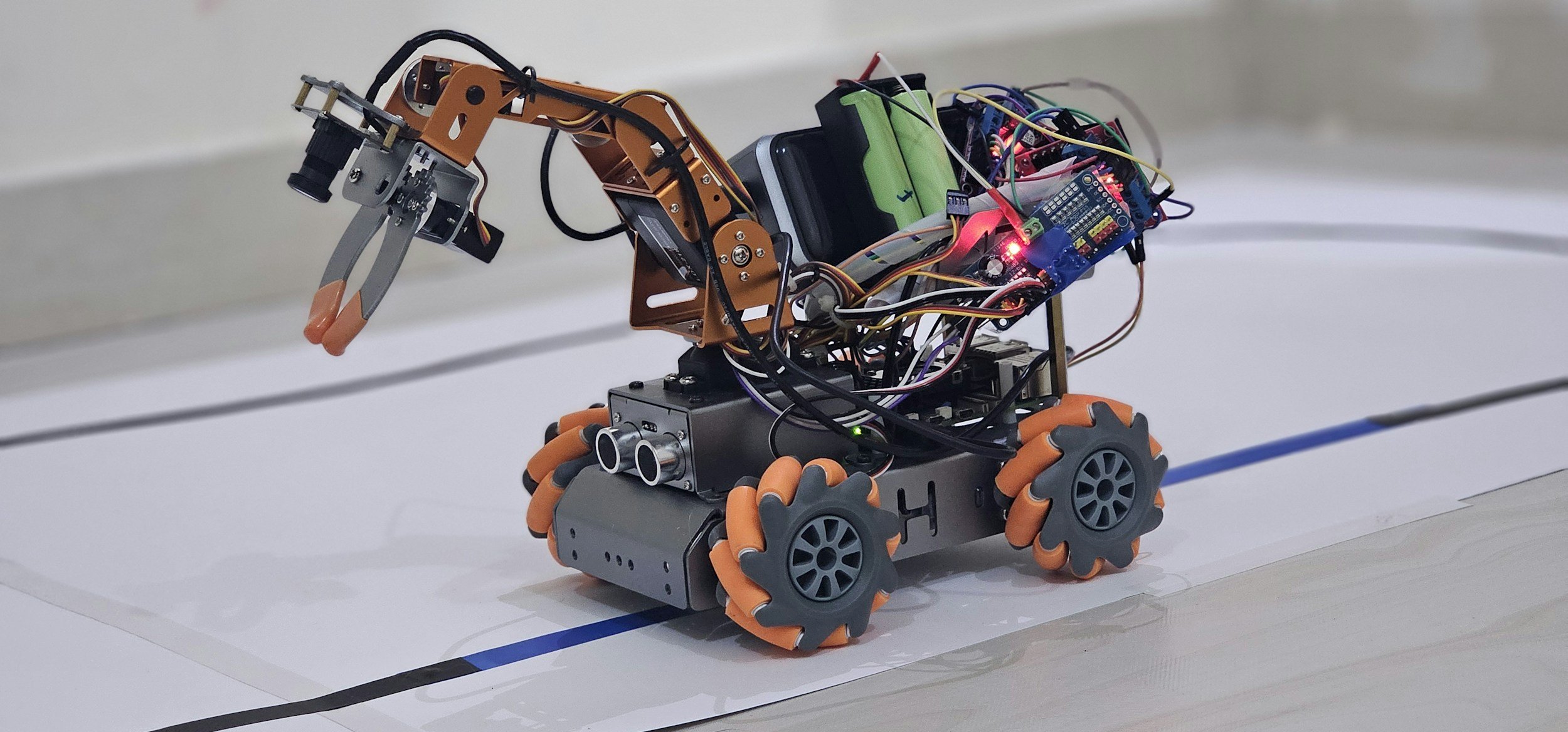 A robotic animal with orange wheels, a robotic arm, and electronic components, moving on a designated track.