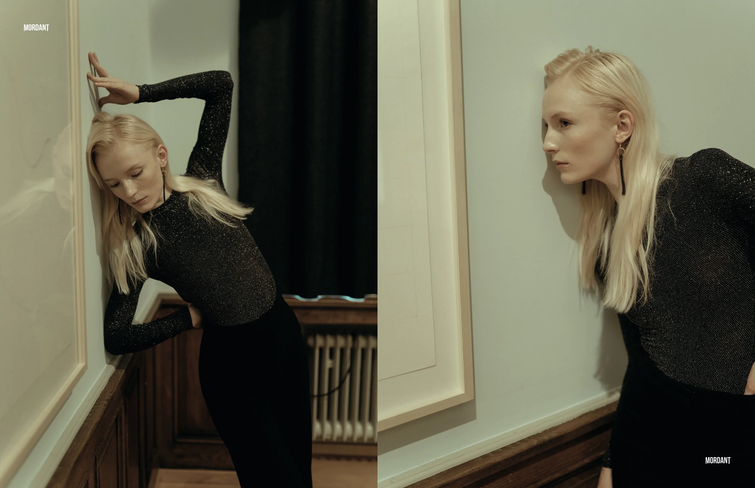 A woman with long blonde hair, wearing a black sparkly top and black pants, standing with her head pressed against a wall in two different poses in a room with white walls, wooden floors, and a radiator.